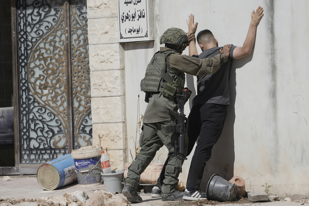 Israeli soldier holds Palestinian man