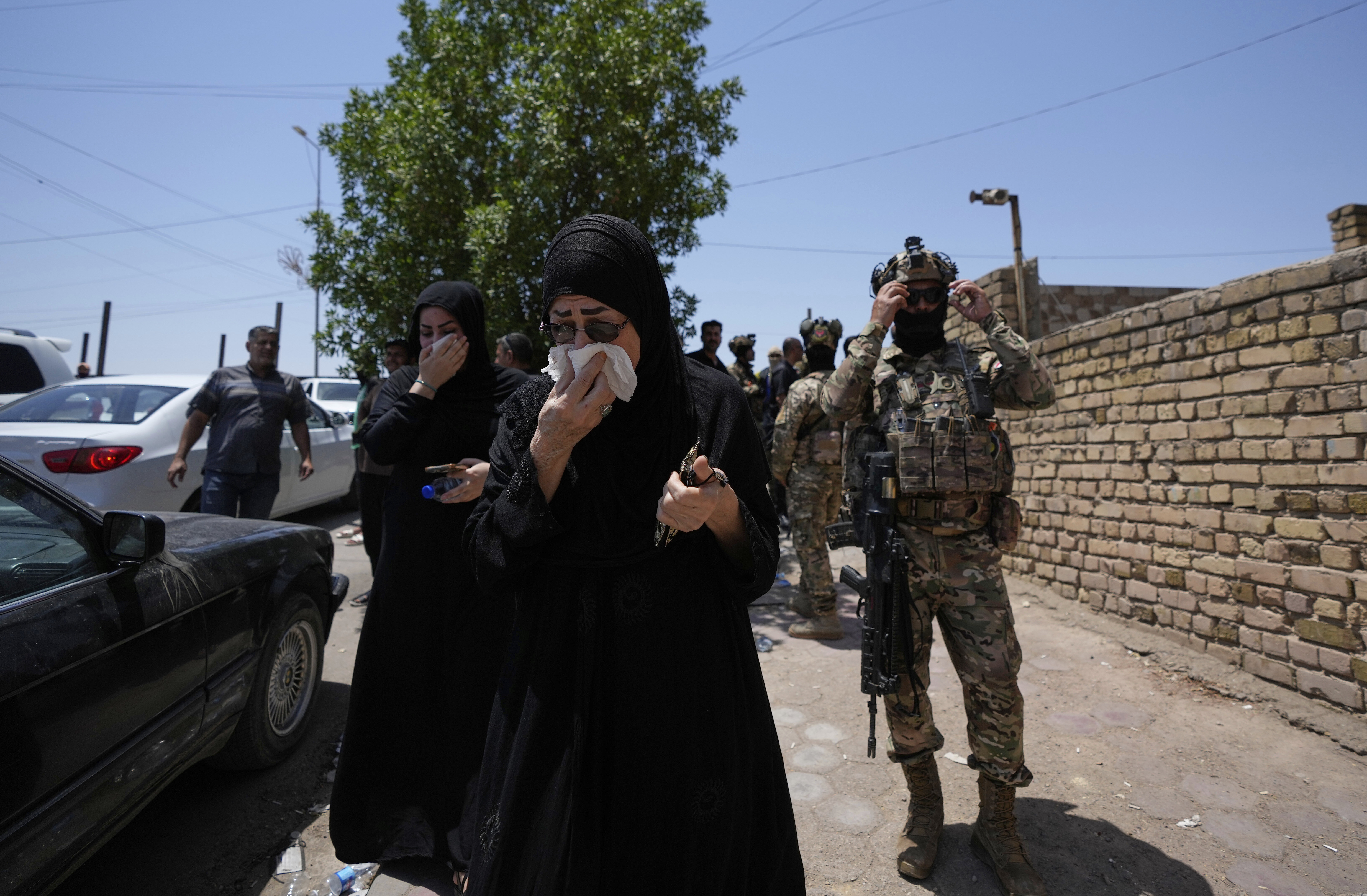Iraqis gather in front of a burning hypermarket building in Kut, Iraq, Thursday, July 17, 2025