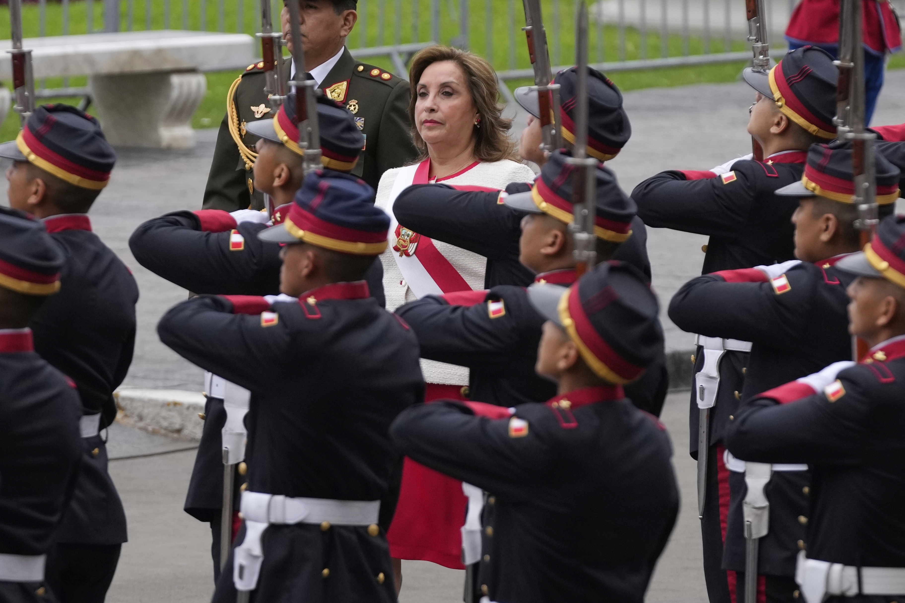 Dina Boluarte surrounded by military members in dress uniform for Peru's Independence Day parade.