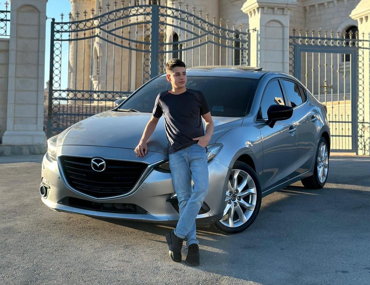 teenager in a black shirt leaning on a silver car