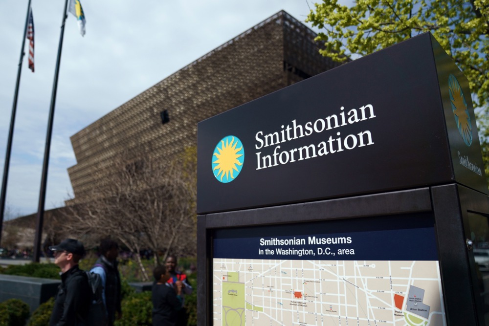 a sign says Smithsonian information in front of a brown building