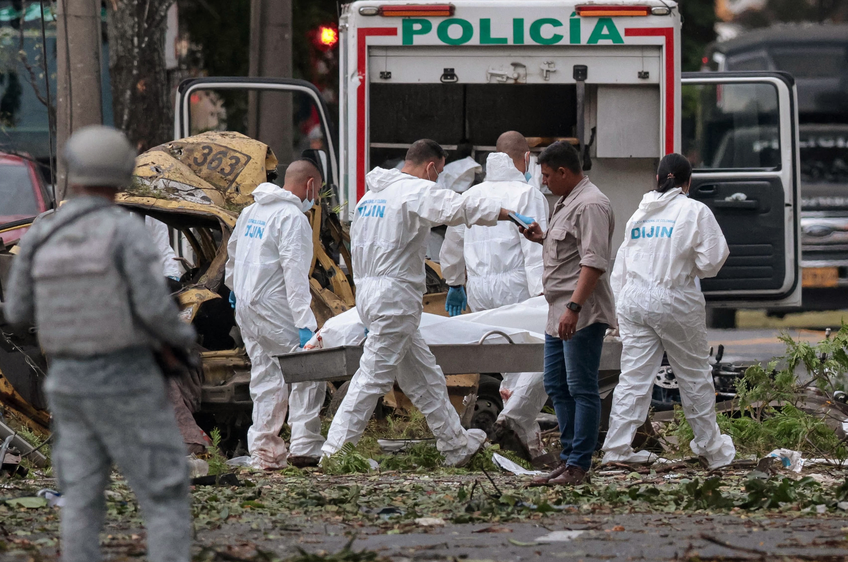 Police officers carry the body of a victim of a bomb explosion in cali, Colombia on August 21 2025. Five people were killed and dozens were injured when a vehicle bomb targeted a military base on a busy street in the Colombian city of Cali on August 21, 2025, local authorities said. (Photo by Iusef Samir Rojas / AFP)