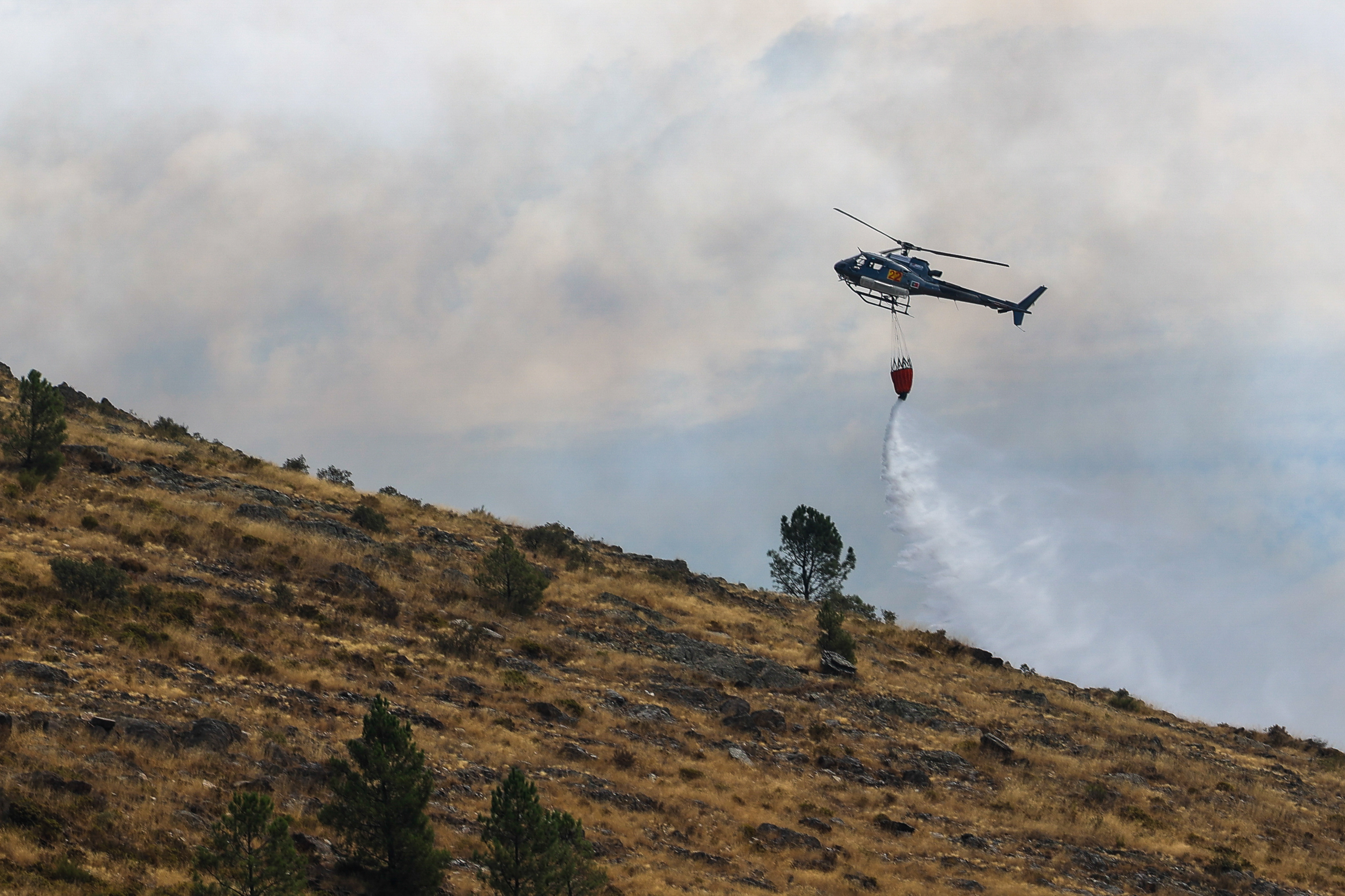 epa12308005 A helicopter flies over a forest fire near Pampilhosa da Serra, Portugal, 18 August 2025. Forest fires have burned in Portugal 185.753 hectares to date, causing two deaths, including a firefighter, and several injuries, most of them minor, and completely or partially destroyed primary and secondary residences, as well as farms, livestock operations, and forest areas. EPA/PAULO NOVAIS