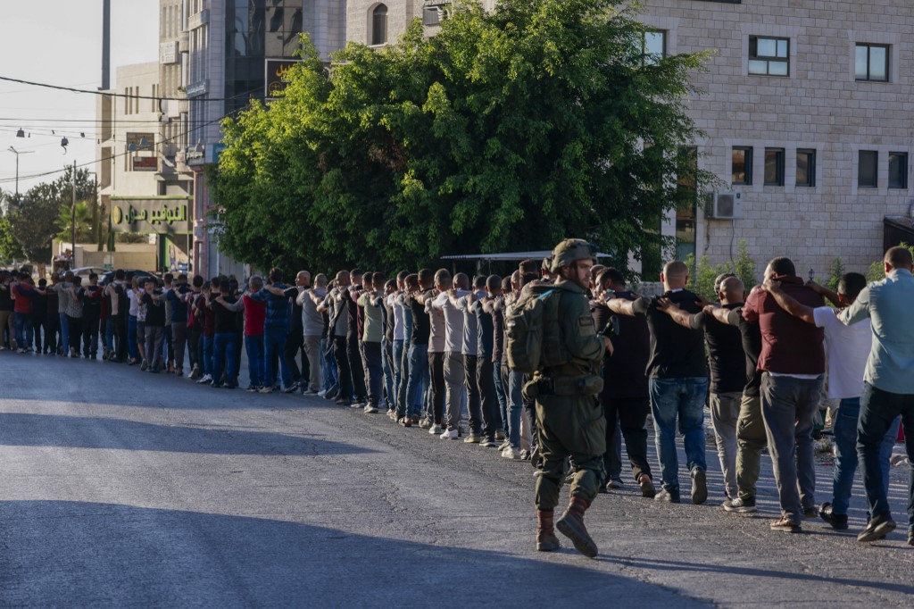 Israeli soldiers arrest random Palestinian men during a raid.