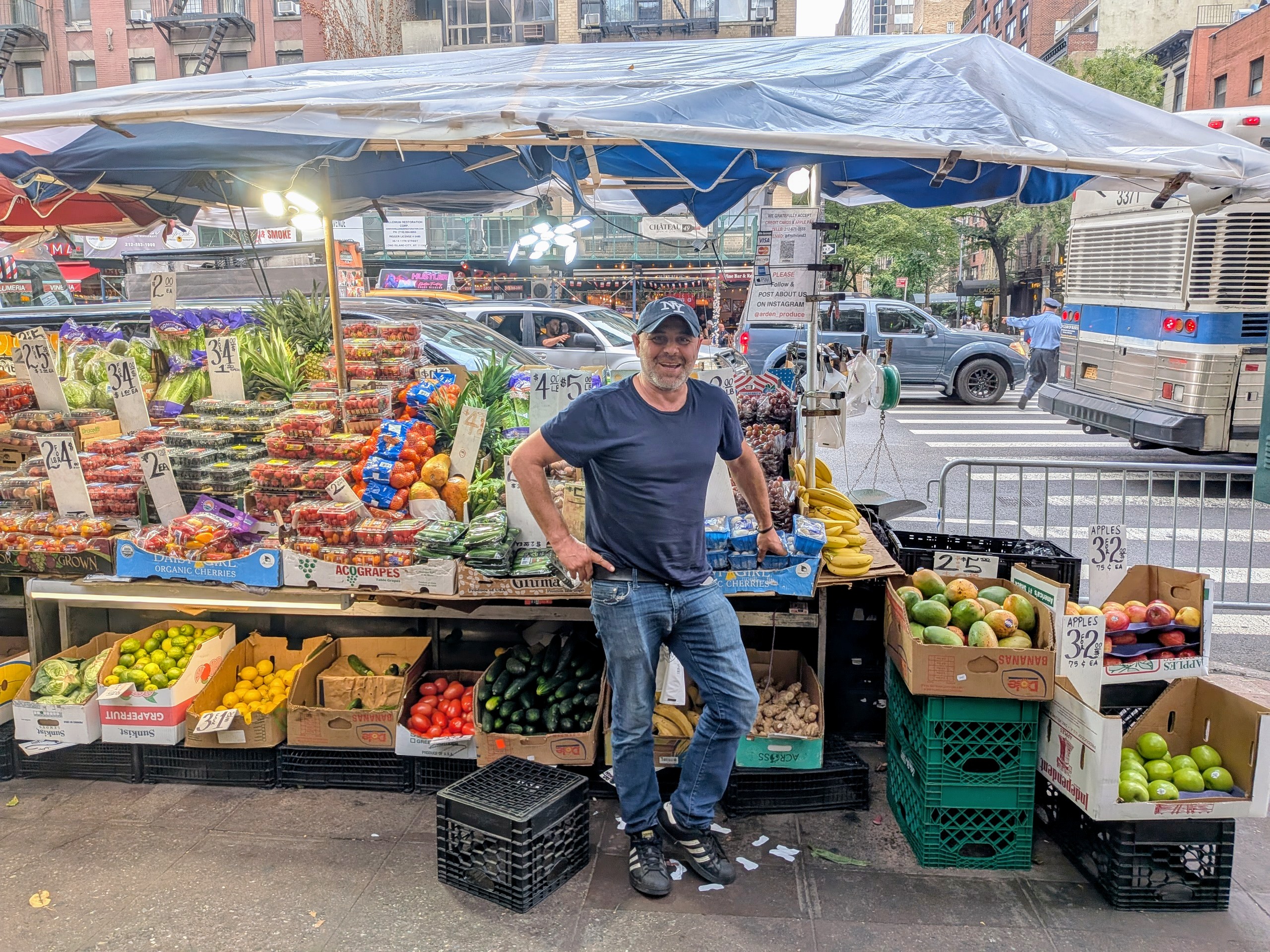 Man poses next to fruit stand