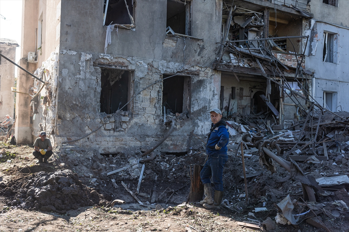 two men in front of an apartment building that is badly damaged