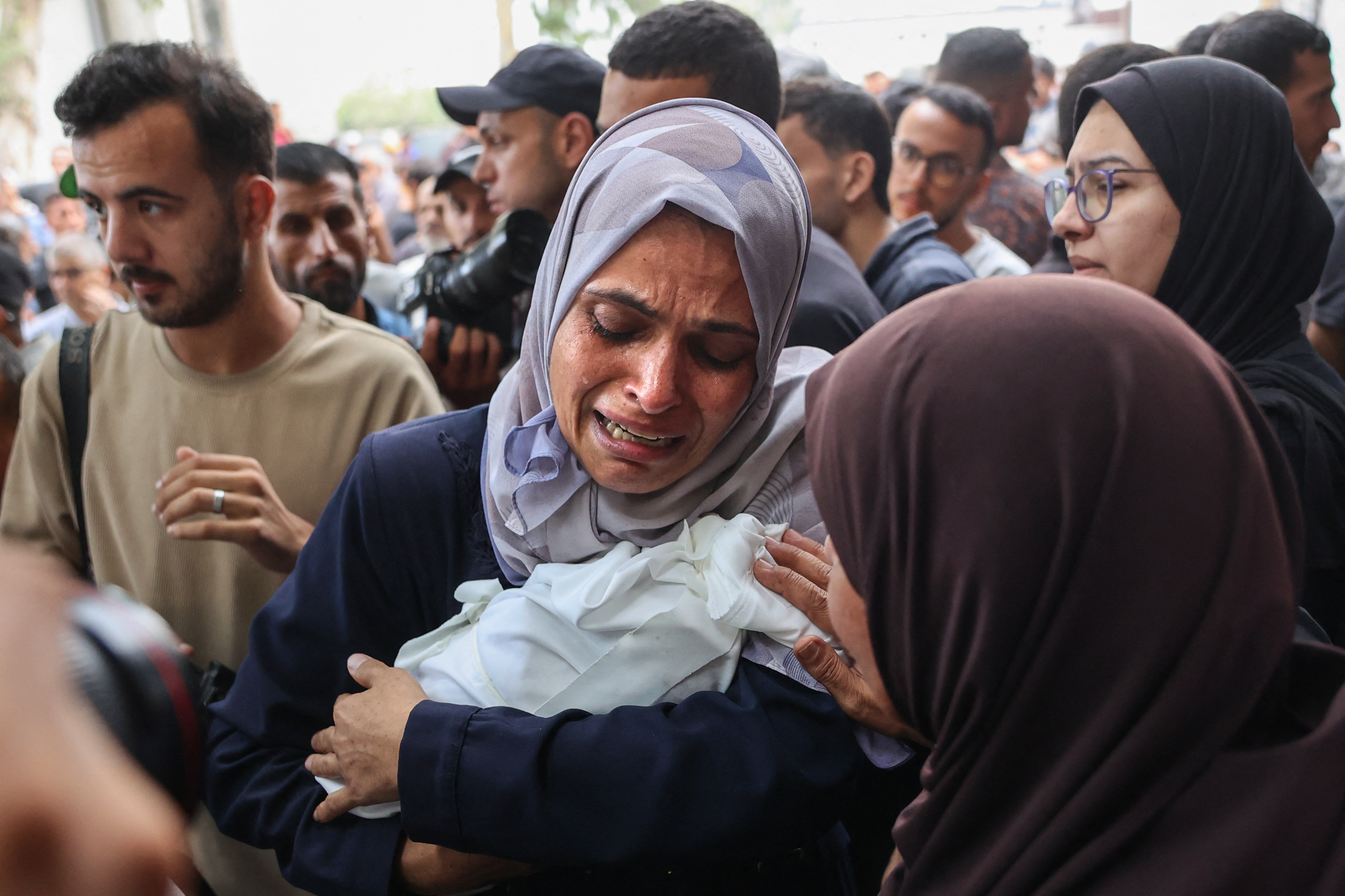 A Palestinian woman carries the body of a baby in Gaza City