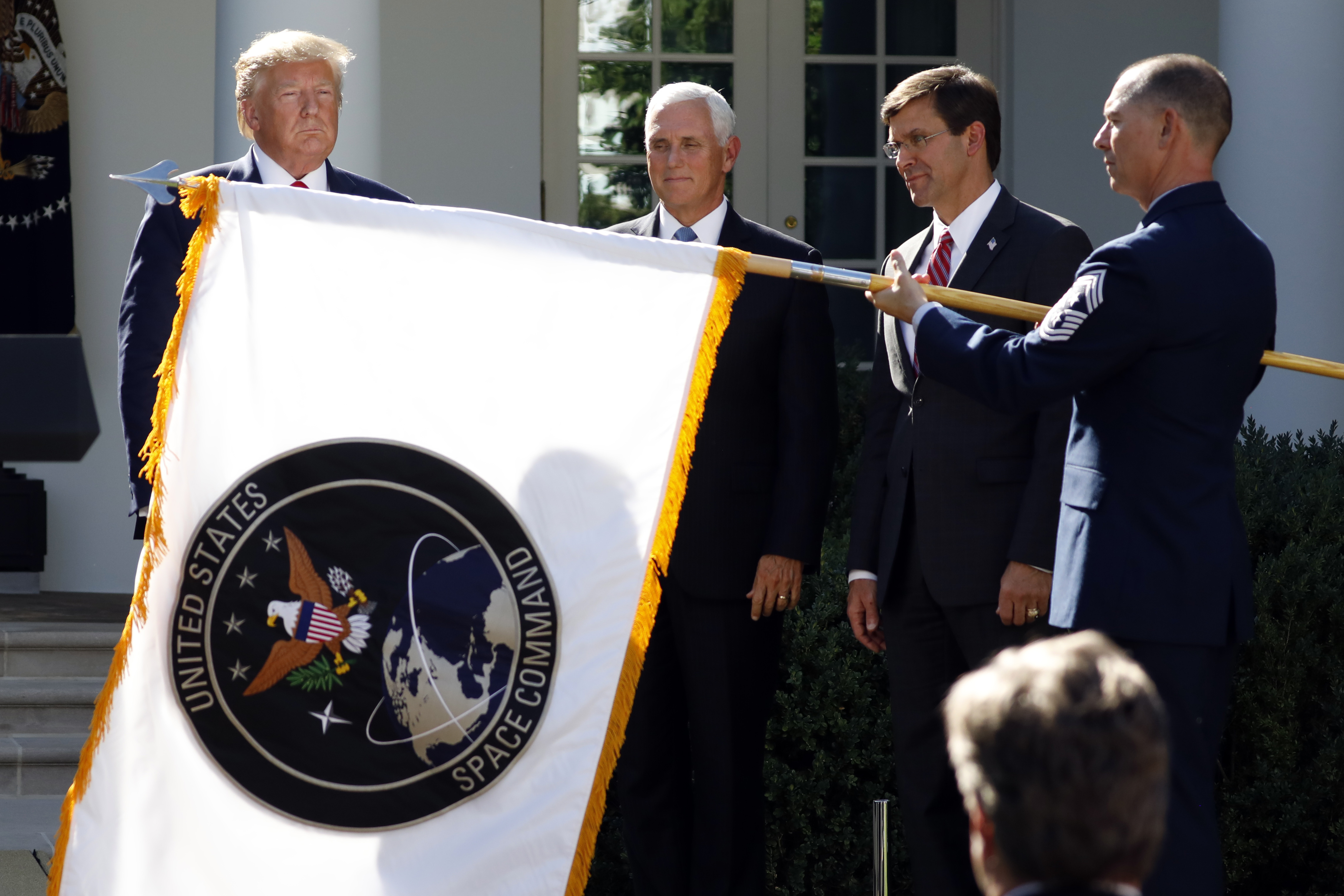 President Donald Trump, left, watches with Vice President Mike Pence and Defense Secretary Mark Esper as the flag for U.S. space Command is unfurled as Trump announces the establishment of US Space Command in the Rose Garden of the White House in Washington on August 29, 2019