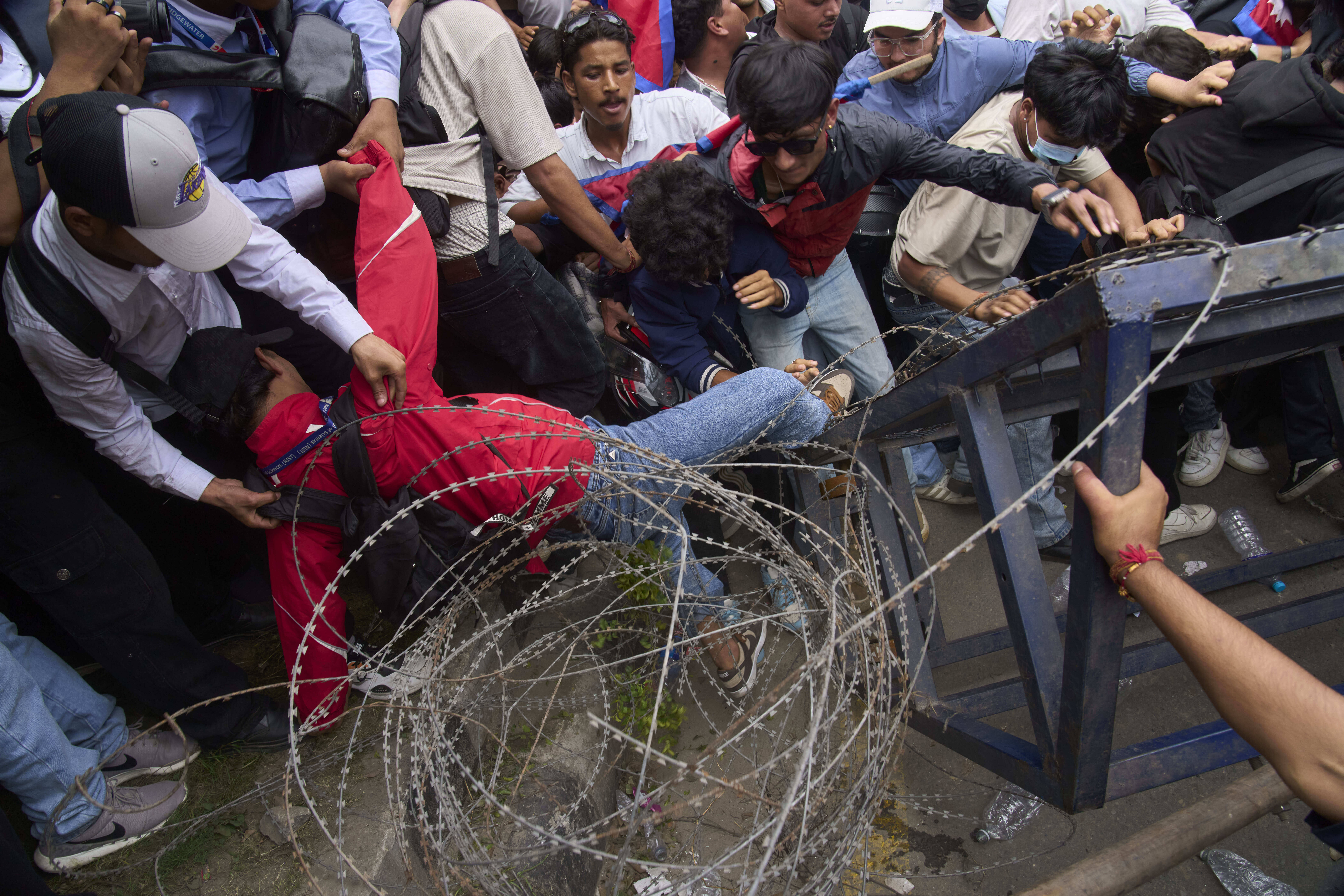 A protester falls down during clashes with riot police outside the parliament building in Kathmandu, Nepal, Monday, Sept. 8, 2025. (AP Photo/Niranjan Shrestha)