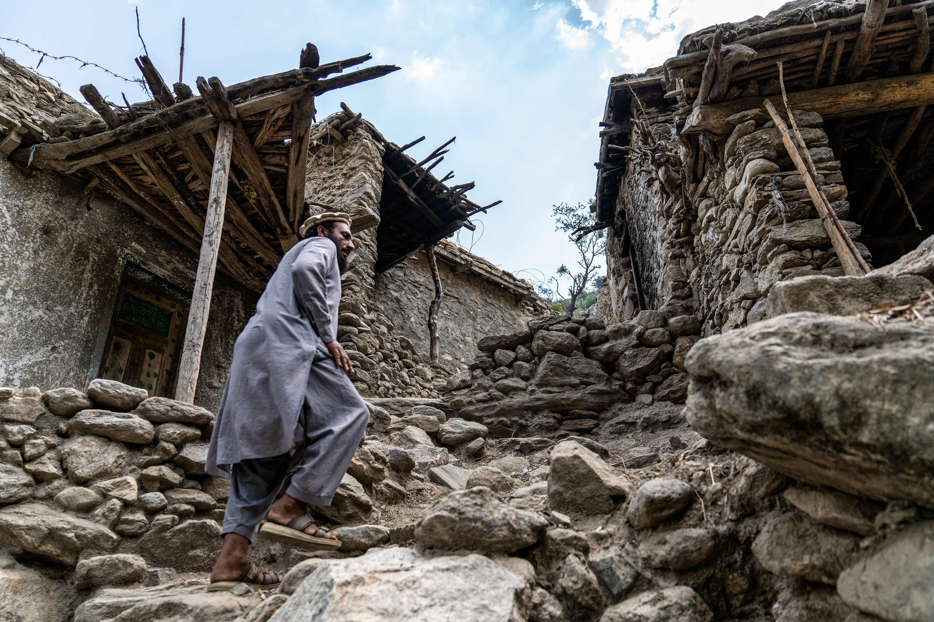 Azim Khan, a 37-year-old farmer walks around damages houses in Gagezu village in Diwa Gul valley