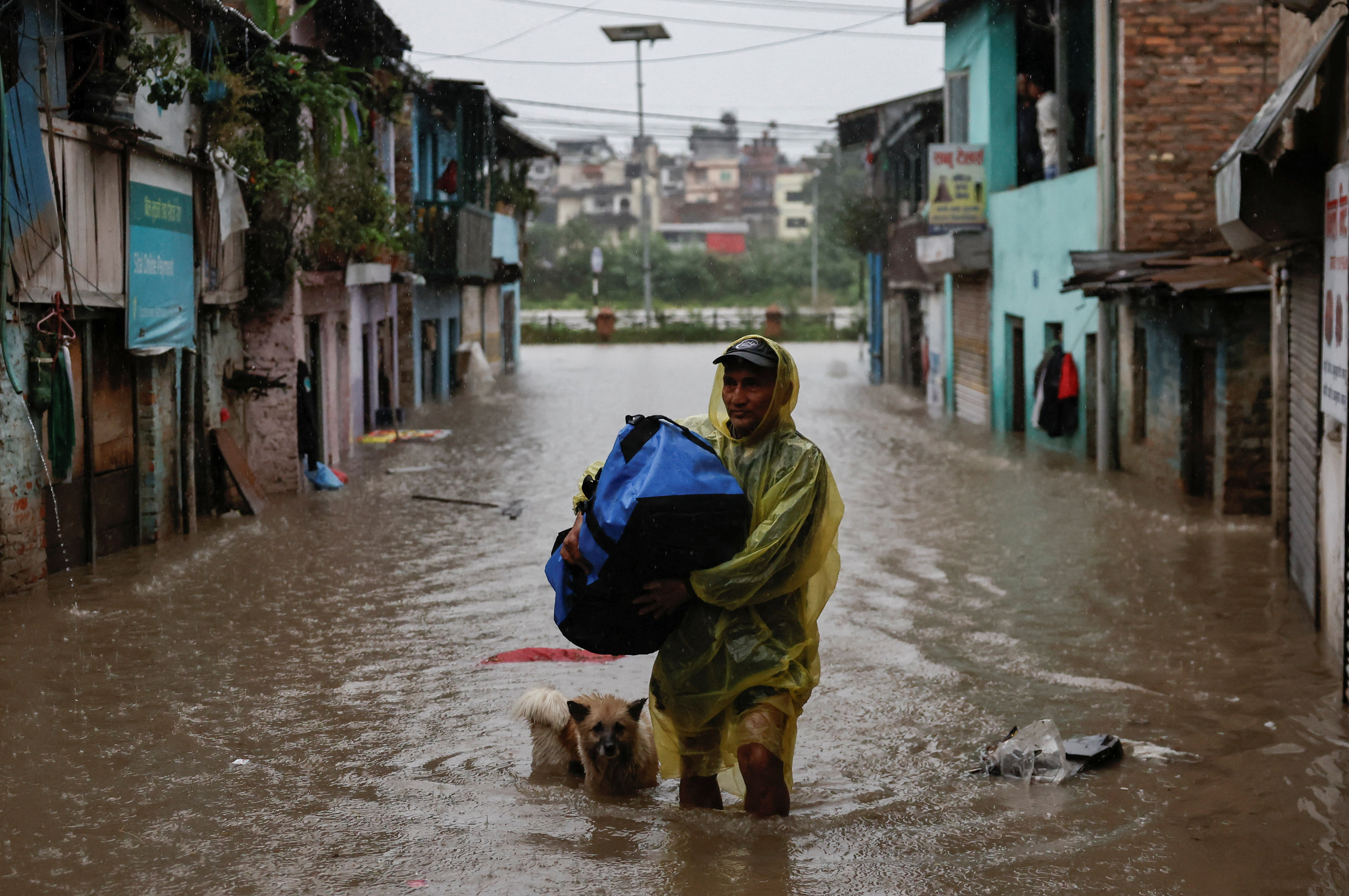 A man carries a bag as he wades through a flooded street near the bank of overflowing Bagmati River, in Nepal's capital, Kathmandu