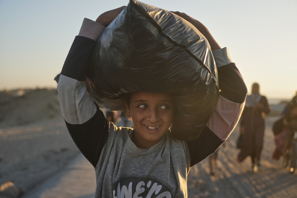 Palestinian girl carrying a back bag over her head