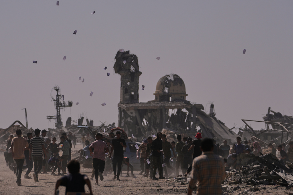 Leaflets being dropped on people by a destroyed mosque