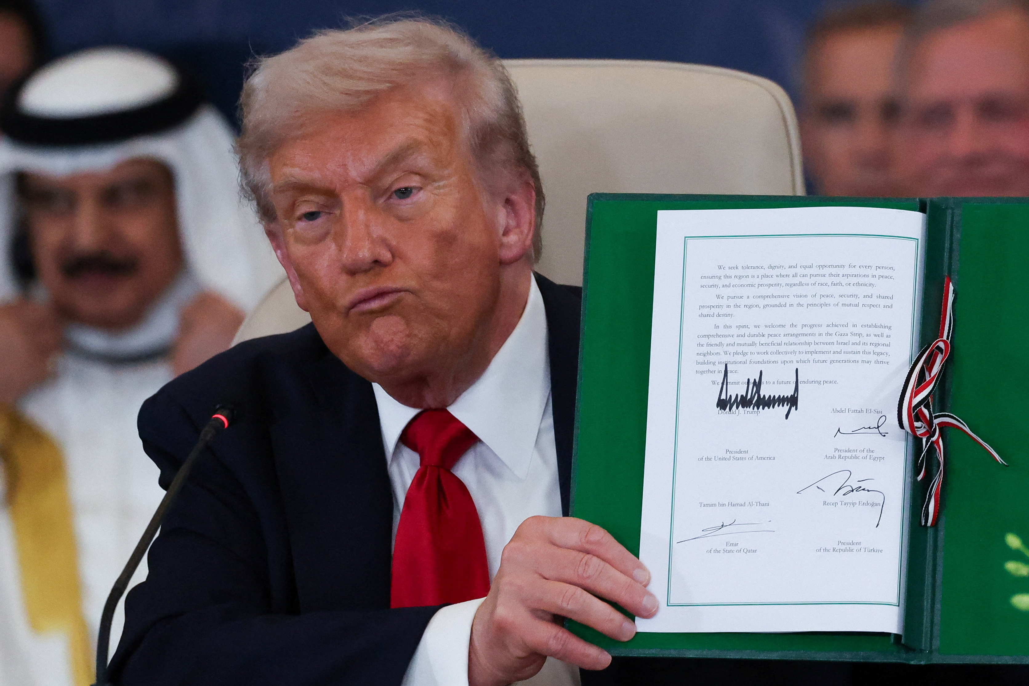 President Donald Trump holds a signed document during a summit to support ending the more than two-year Israel-Hamas war in Gaza after a breakthrough ceasefire deal, Monday, Oct. 13, 2025, in Sharm El Sheikh, Egypt. (Suzanne Plunkett/Pool via AP)