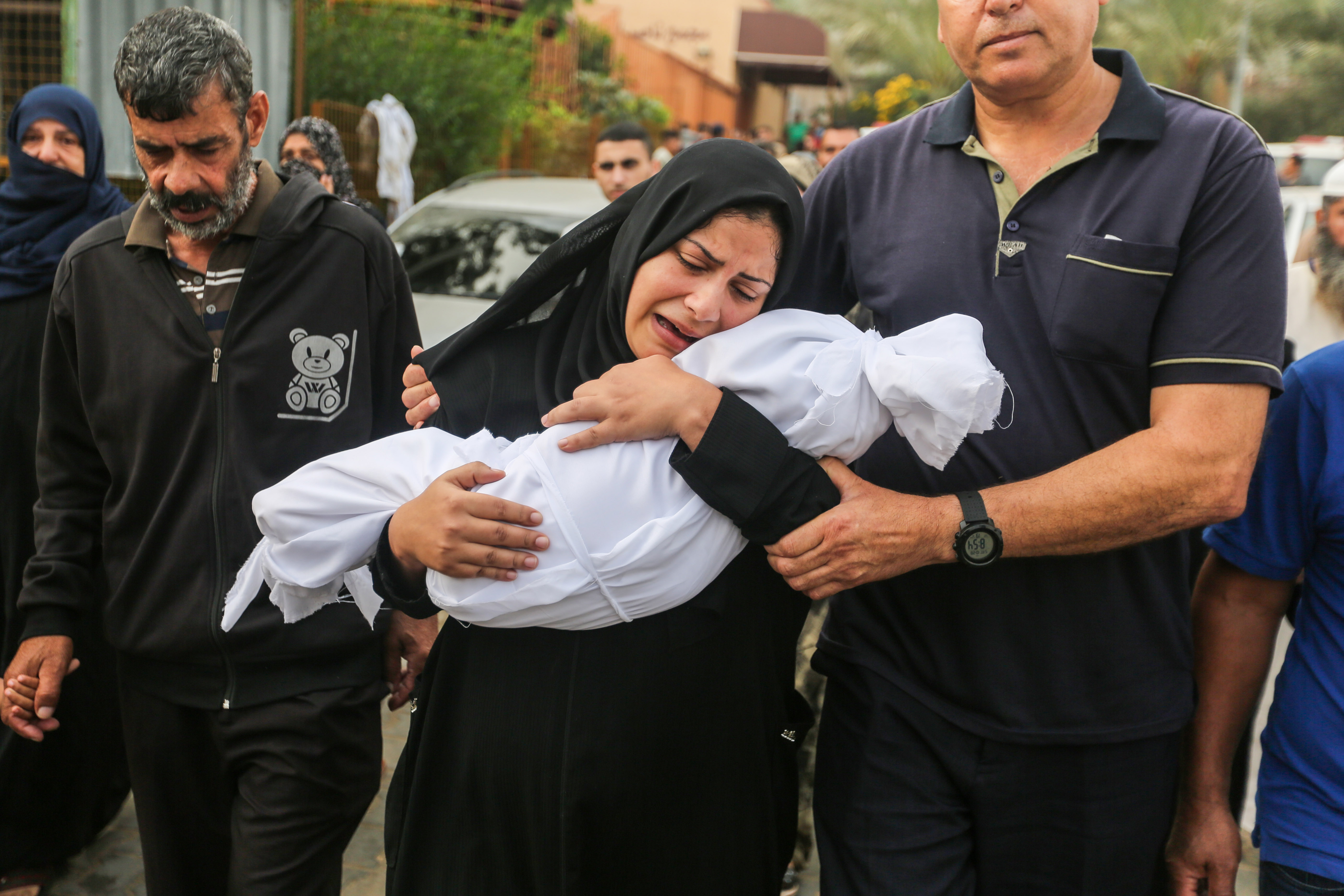 A woman cradles her son, eight-month-old Muhammad Bilal Abu Salah, as residents collect the bodies of Palestinians killed in Israeli air raids