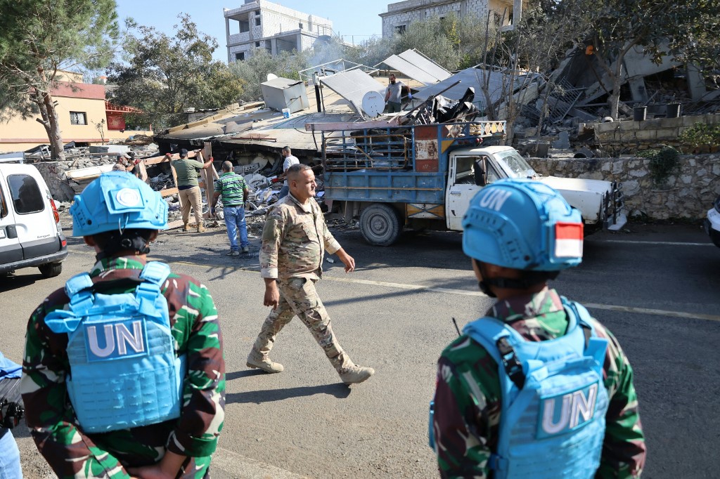 UNIFIL peacekeepers watch workers as they remove the rubble from a site targeted overnight by an Israeli air raid in the southern Lebanese village of Et Taybeh