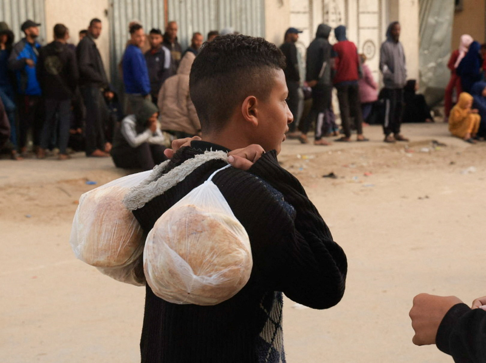 A youth carries bags with bread