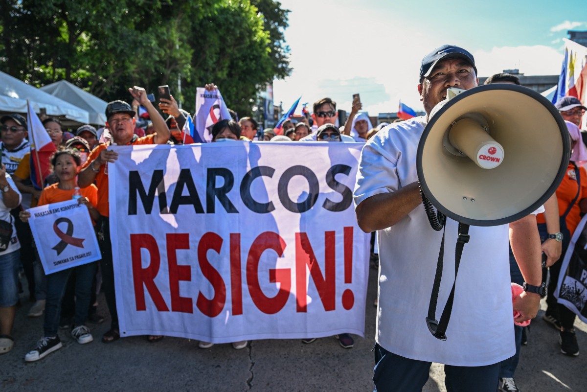 Protesters hold a banner calling for the resignation of Philippine President Ferdinand Marcos Jr during a rally.