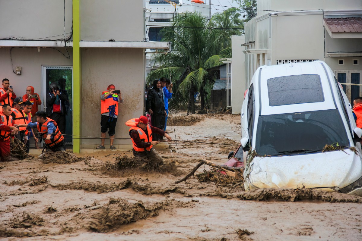 A man carries his child as he wades through floodwaters