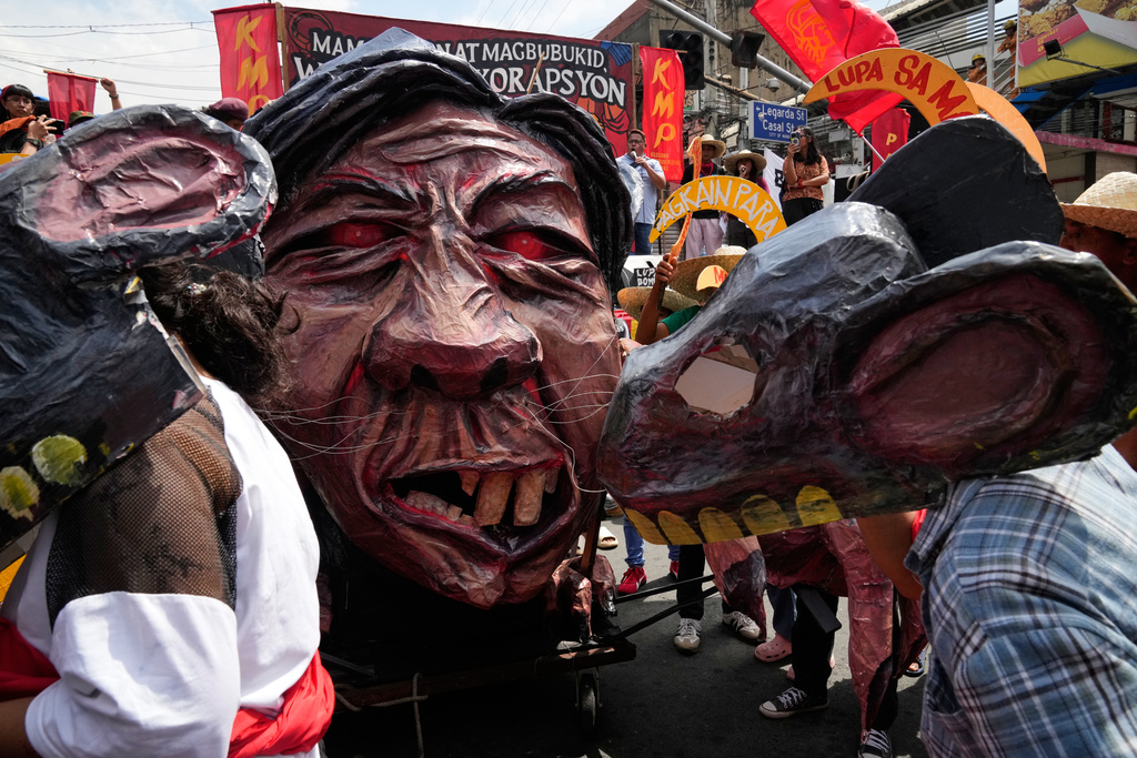 Protesters wearing rat masks walk beside an effigy of Philippine President Ferdinand Marcos Jr during a farmer-led anticorruption rally on Tuesday, October 21, 2025, near the Malacanang presidential palace in Manila, Philippines