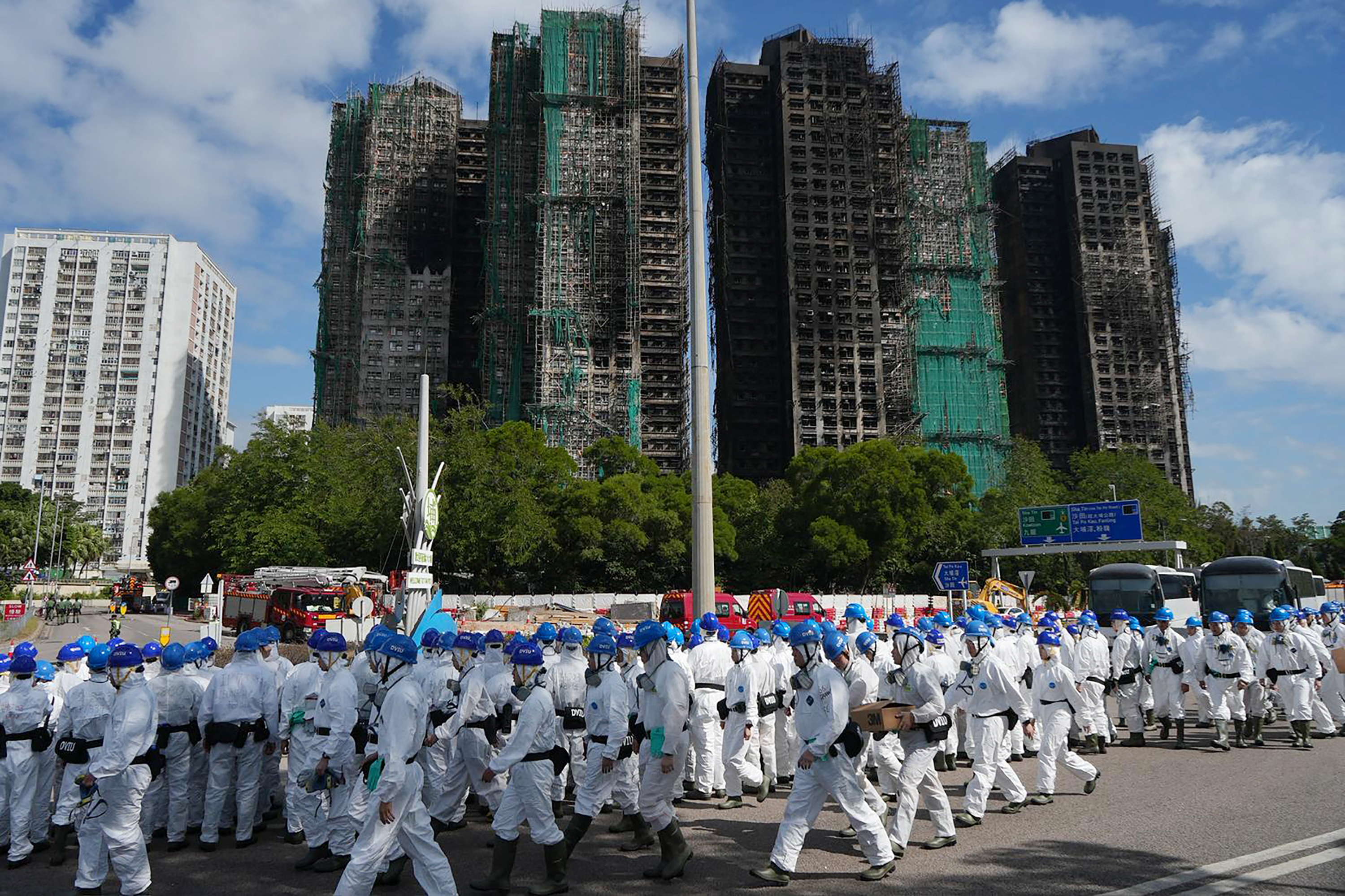 Police officers from the Disaster Victim Identification Unit (DVIU), dressed in white-coloured full-body protective gear, gather by the housing blocks of Wang Fuk Court in the aftermath of the deadly November 26 fire, in Hong Kong on November 29, 2025.