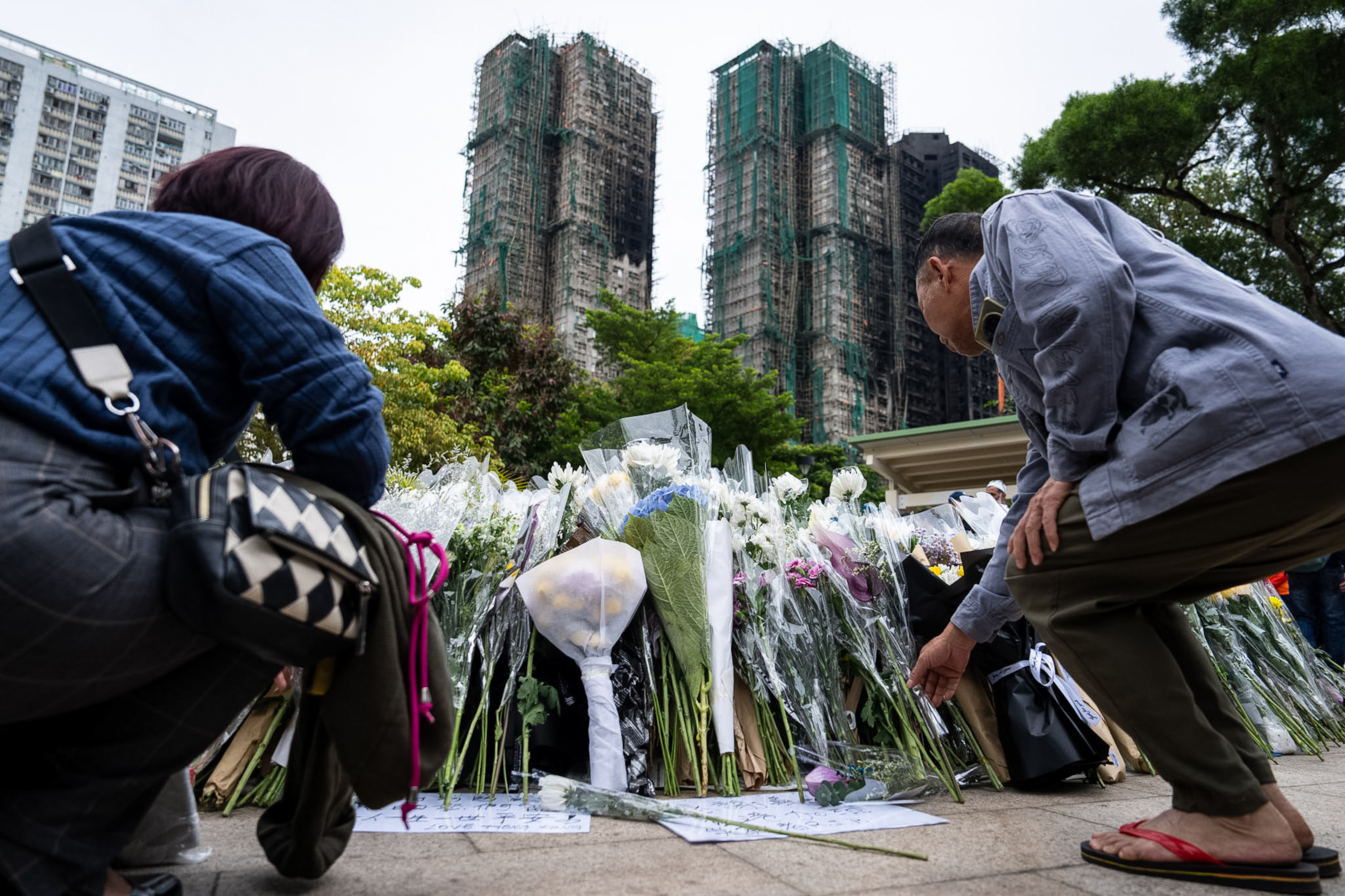 People offer flowers for the victims near the site of a deadly Wednesday fire at Wang Fuk Court, a residential estate in the Tai Po district of Hong Kong's New Territories on Sunday, Nov. 30, 2025. (AP Photo/Chan Long Hei)