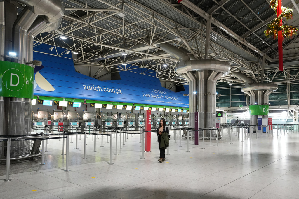 A woman walks through a nearly deserted hall of the Lisbon airport amid strike