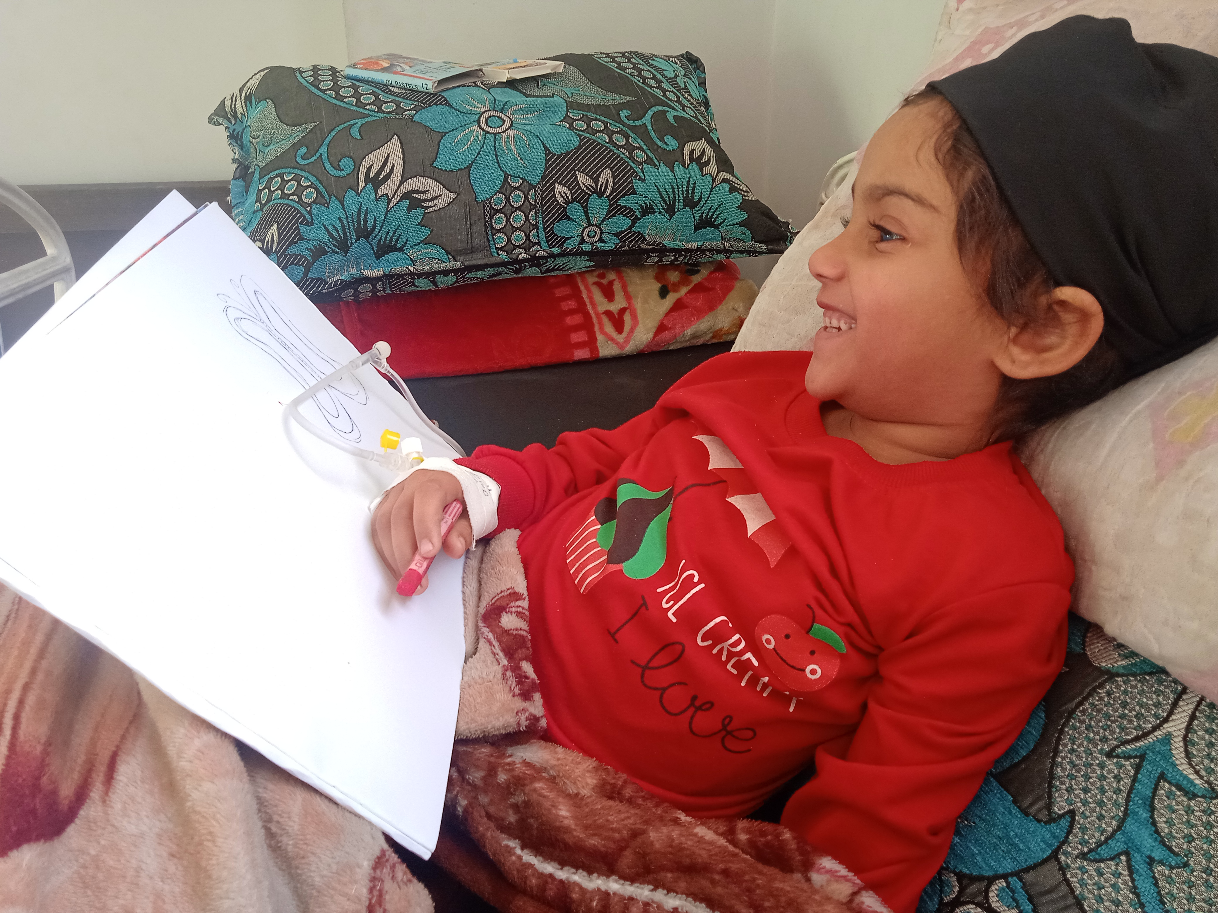 Sudnus, trying to draw, in her hospital bed [Courtesy of Eman Hillis]