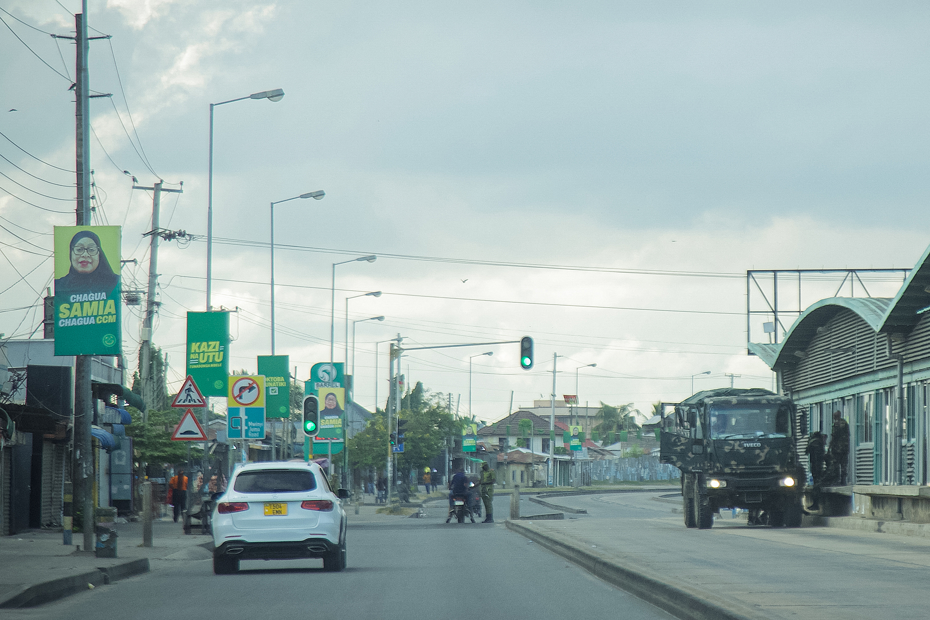 An electoral poster of Tanzania's President Samia Suluhu Hassan is seen as police officers inspect vehicles at a deserted intersection in Dar Es Salaam on December 9, 2025 during a day of demonstrations agaisnt the violent crackdown by security forces on election demonstrations. (Photo by AFP)