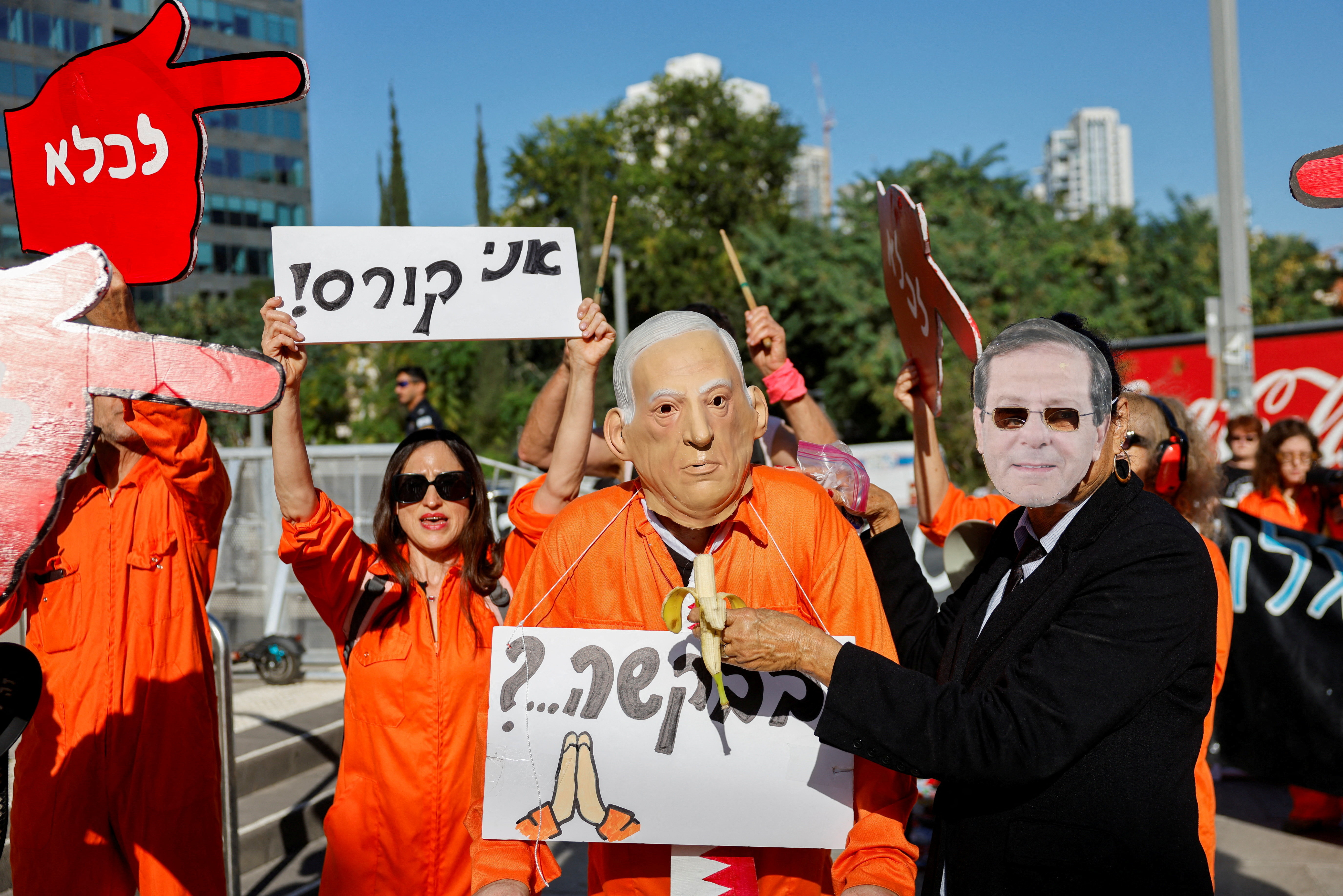 A demonstrator wearing a mask depicting Israeli President Isaac Herzog pretends to feed a banana to another demonstrator wearing a mask depicting Israeli Prime Minister Benjamin Netanyahu during a protest after Netanyahu requested a pardon in his corruption trial, outside a courthouse in Tel Aviv, Israel, December 1, 2025. REUTERS/Amir Cohen