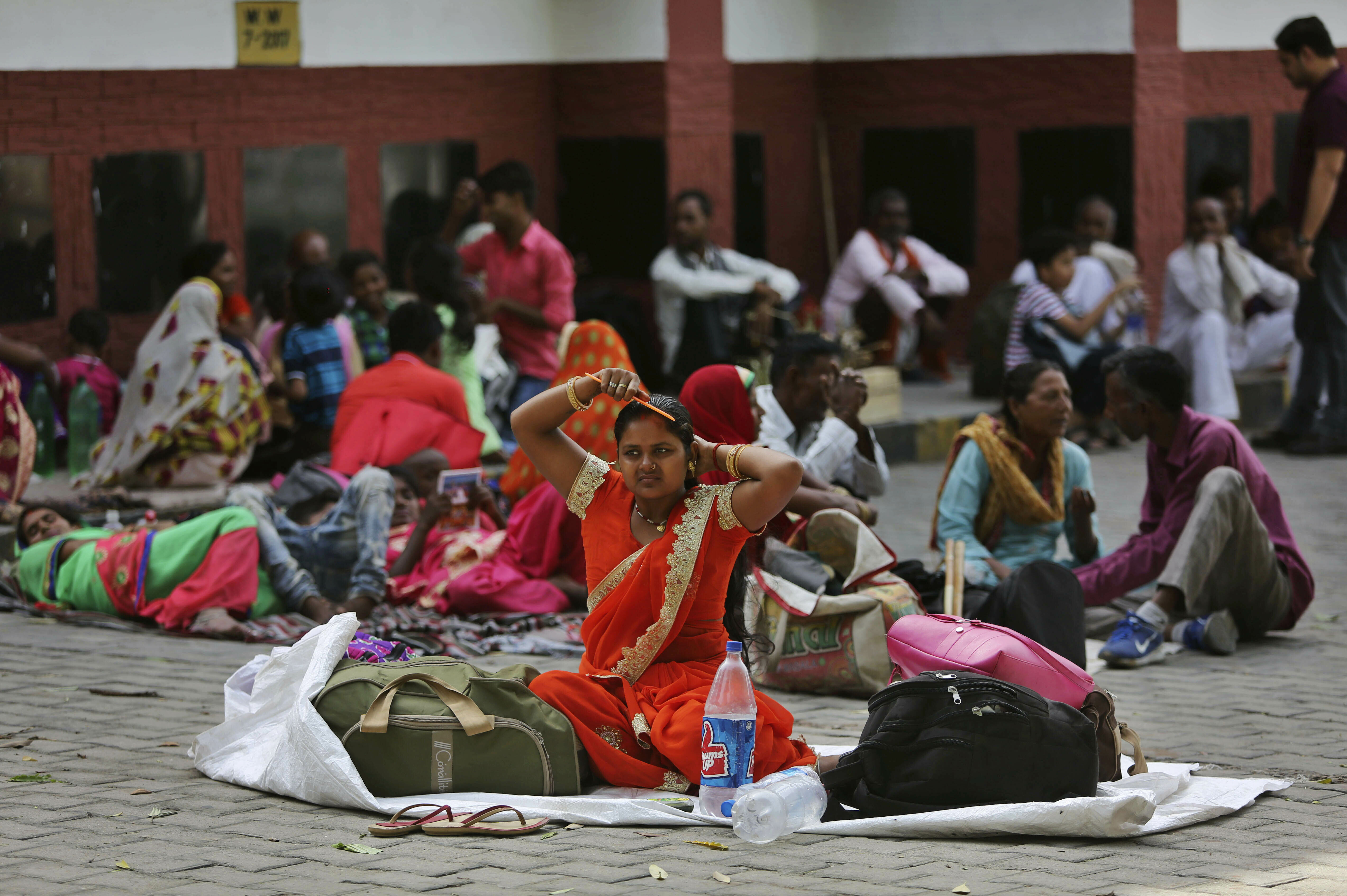 Hindu pilgrims on their way to the Vaishno Devi shrine rest under a shade and wait for transport outside a railway station on a hot day in Jammu, India, Wednesday, June 12, 2019. Intense heat wave continues to plague northern India, with several areas across the region, hitting temperatures above 46 degrees Celsius (115 degrees Fahrenheit). (AP Photo/Channi Anand)