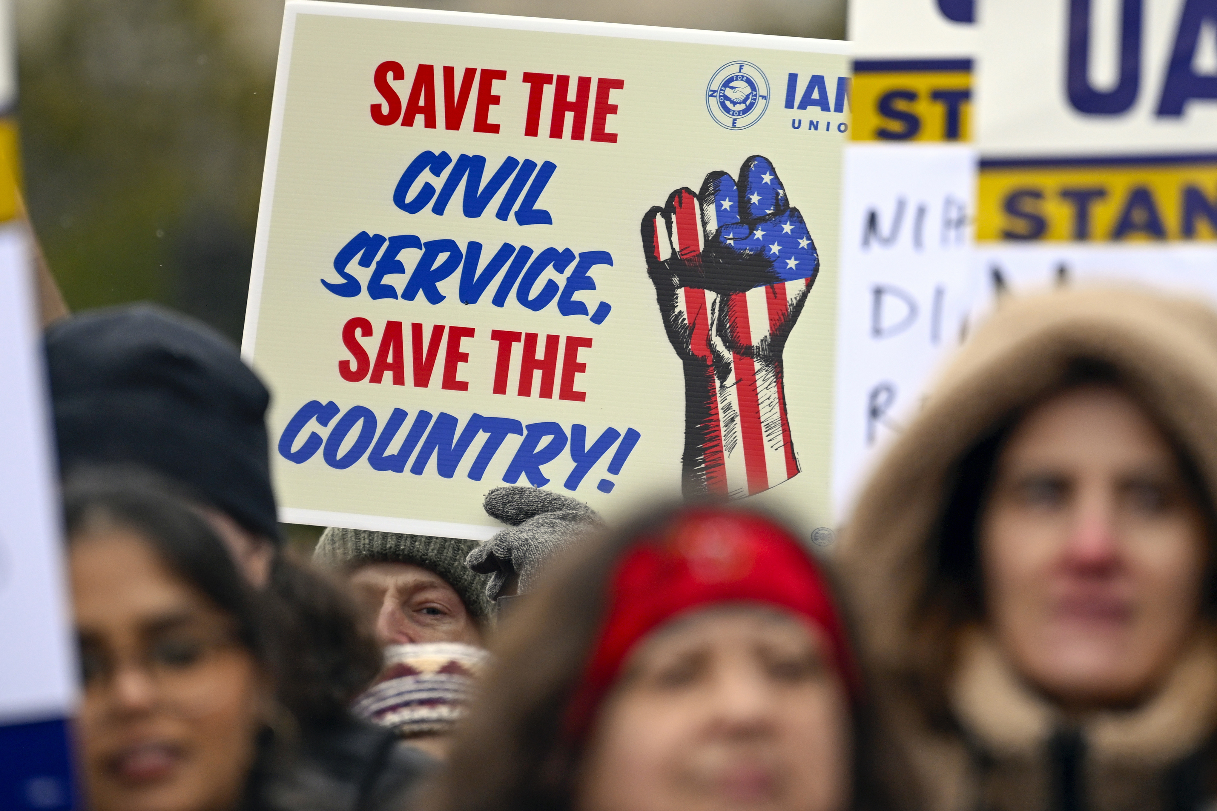 Protesters hold signs that read, "Save the Civil Service."