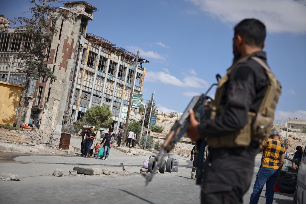 Syrian security forces stand guard as residents leave a neighbourhood.