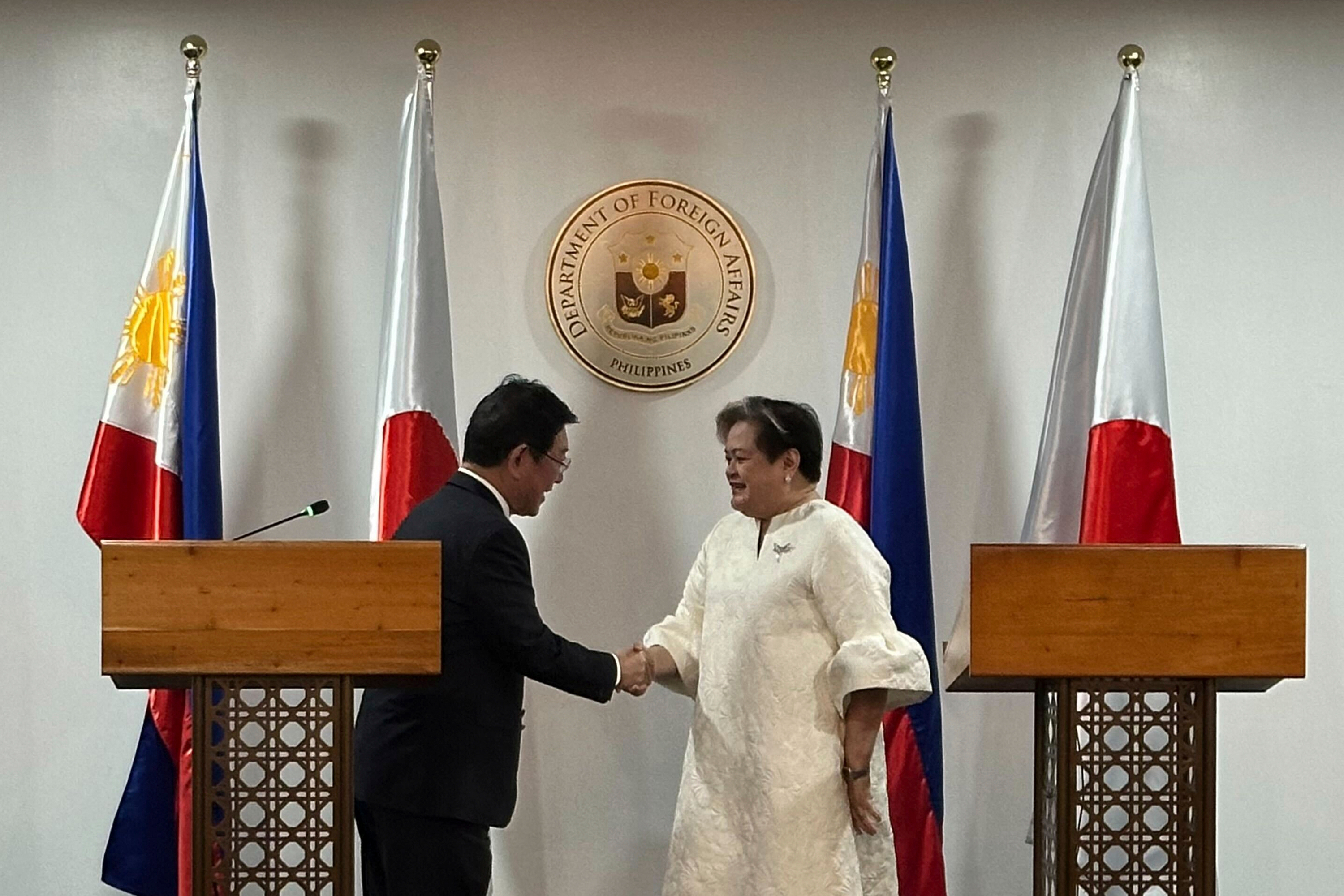 Japanese Foreign Minister Toshimitsu Motegi, left, and Philippine Foreign Secretary Theresa Lazaro shake hands.