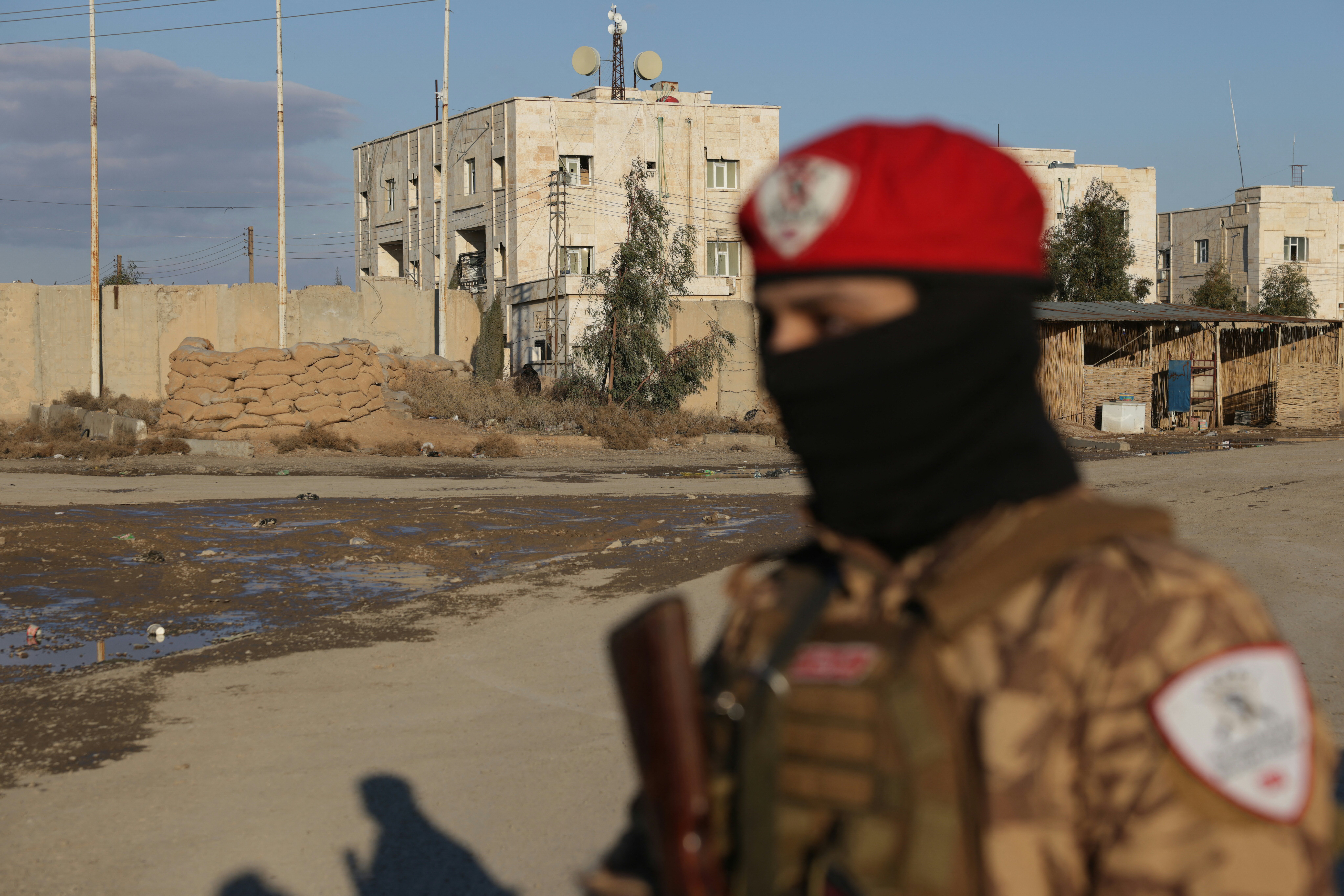 A Syrian government soldier stands outside SDF controlled Al Aktan prison which holds ISIL detainees