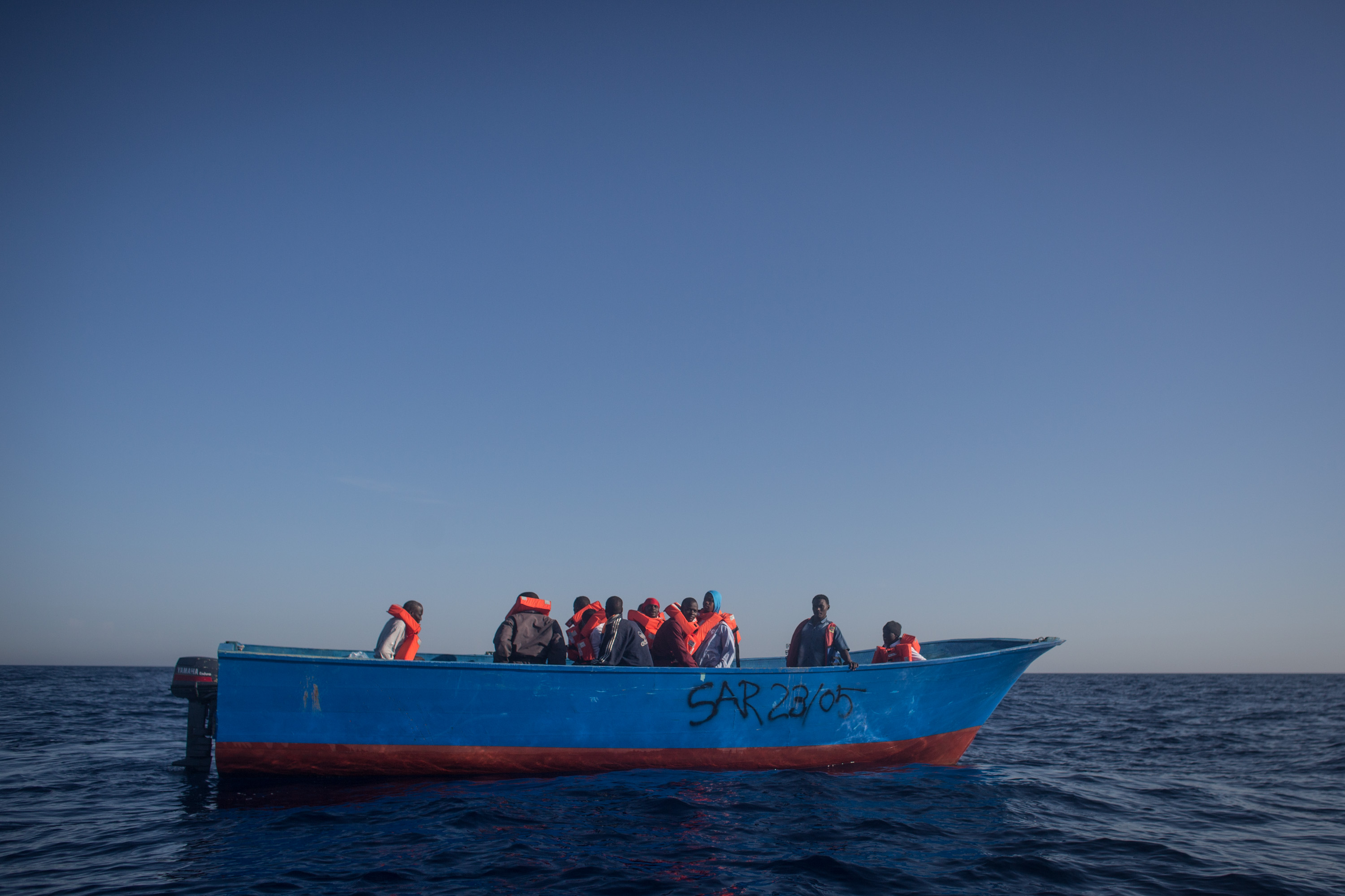 LAMPEDUSA, ITALY - JUNE 10: Refugees and migrants wait in a small wooden boat to be rescued by crewmembers from the Migrant Offshore Aid Station (MOAS) Phoenix vessel on June 10, 2017 off Lampedusa, Italy. An estimated 230,000 refugees and migrants will arrive in Italy this year as numbers of refugees and migrants attempting the dangerous central Mediterranean crossing from Libya to Italy continues to rise since the same time last year. So far this year more than 58,000 people have arrived in Italy and 1,569 people have died attempting the crossing. Libya continues to be the primary departure point for refugees and migrants taking the central Mediterranean route to Sicily. In an attempt to slow the flow of migrants, Italy recently signed a deal with Libya, Chad and Niger outlining a plan to increase border controls and add new reception centers in the African nations, which are key transit points for migrants heading to Italy. MOAS is a Malta based NGO dedicated to providing professional search-and-rescue assistance to refugees and migrants in distress at sea. Since the start of the year MOAS have rescued and assisted more than 4000 people and are currently patrolling and running rescue operations in international waters off the coast of Libya. (Photo by Chris McGrath/Getty Images)