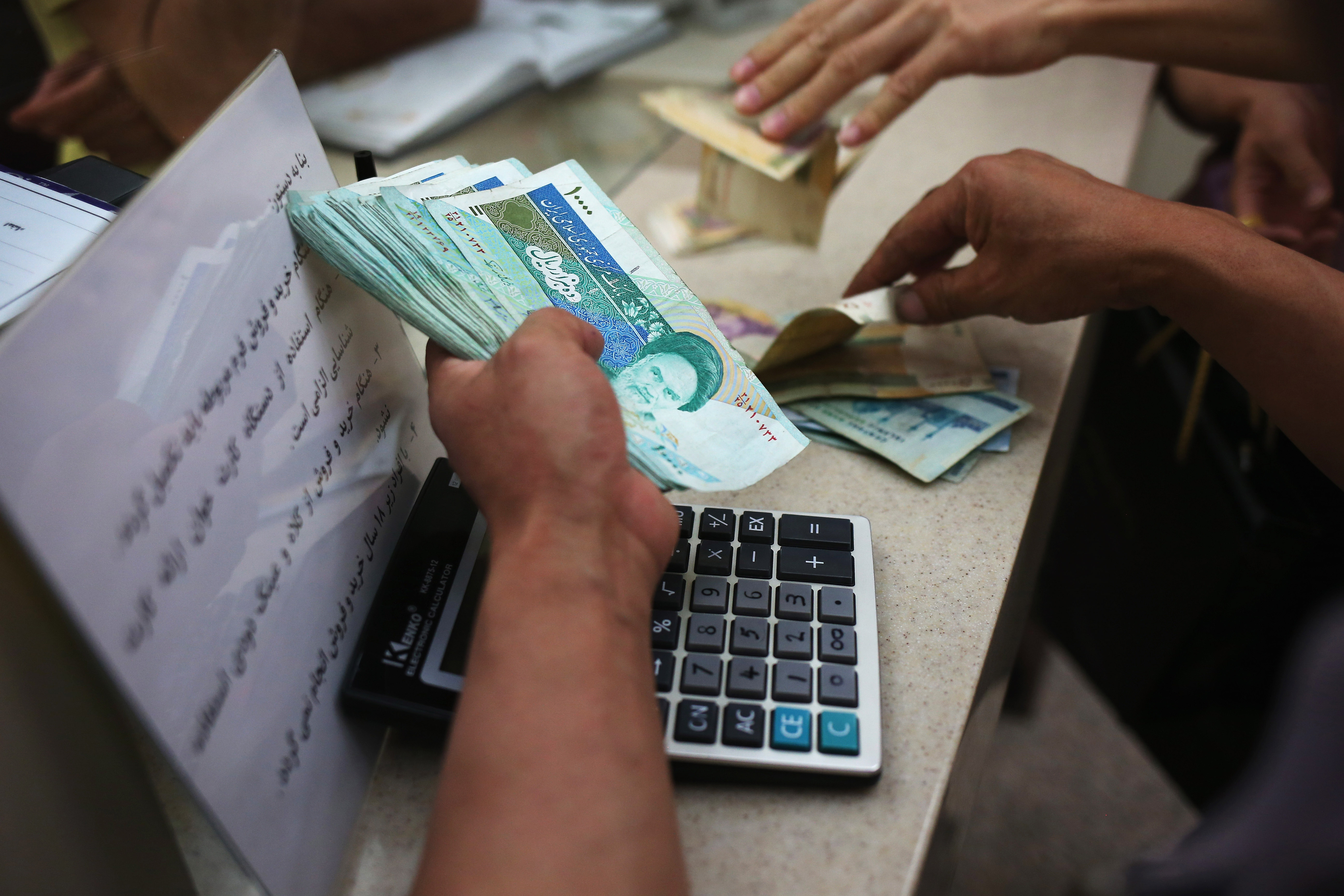ISFAHAN, IRAN - JUNE 02: People change foreign currency for Iranian Rials at an exchange shop in the new Isfahan City Center shopping mall on June 2, 2014 in Isfahan, Iran. The mall, still under construction, is the largest shopping center in Iran and will include a 5-star hotel, a financial center and an entertainment center with cinema and fair complex. The mall is being built by Prestige Land Iran and was designed by architect Madardo Cadiz of Cadiz International. Historic Isfahan, with it's immense mosques, picturesque bridges and ancient historic bazaar, is a virtual living museum of Iranian traditional culture. It's also the Iran's top tourist destination for both Iranian and domestic visitors. On June 4 Iran marks the 25th anniversary of the death of the Ayatollah Khomeini and his legacy of the Islamic Revolution. (Photo by John Moore/Getty Images)