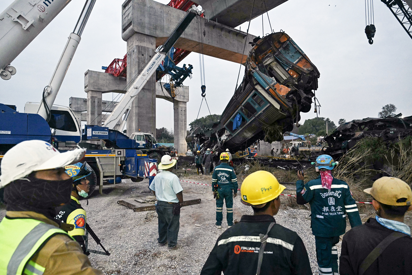 Recovery workers watch as a carriage of a train that crashed when a construction crane collapsed is lifted off the tracks in Thailand's Nakhon Ratchasima province on Jan. 14, 2026. A crane at a China-backed high-speed rail project in Thailand collapsed onto a passenger train on January 14 and caused it to derail, killing at least 28 people and injuring dozens more, authorities said. [Lillian Suwanrumpha/AFP]