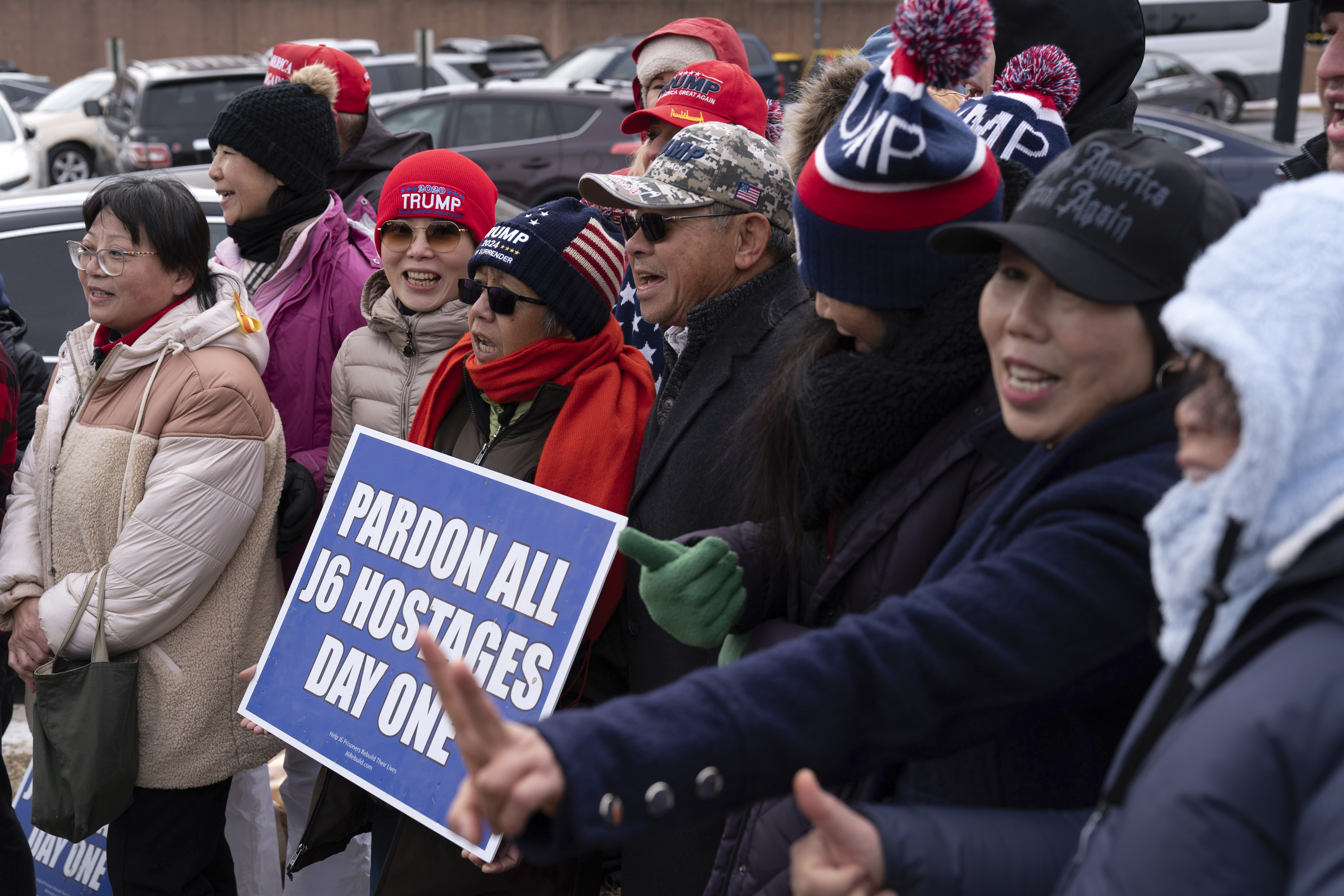 Trump supporters hold up a sign that reads, "Pardon all J6 hostages day one"