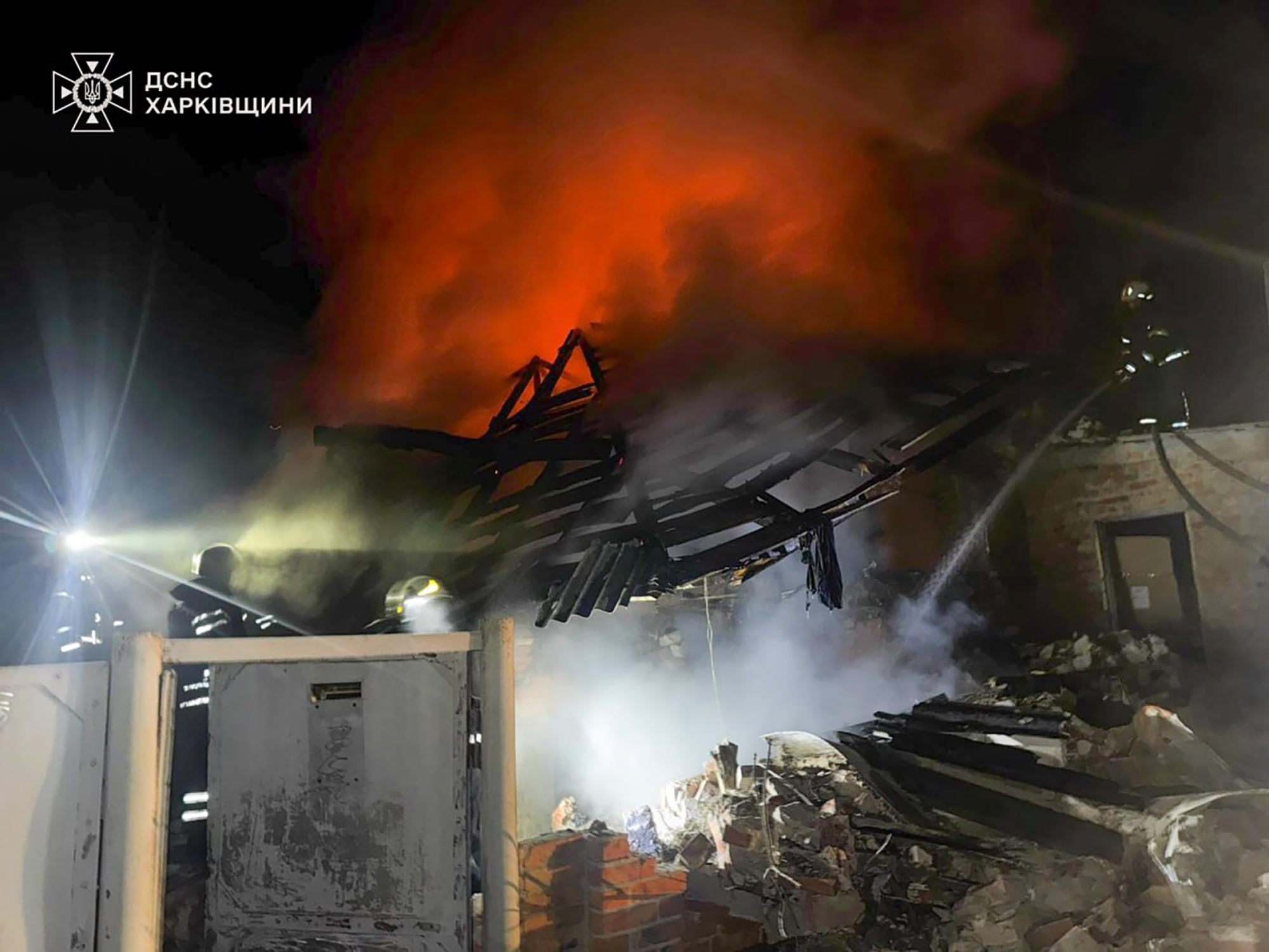In this photo provided by the Ukrainian Emergency Service, emergency services personnel work to extinguish a fire at a private house following a Russian air attack in Bohodukhiv, Kharkiv region