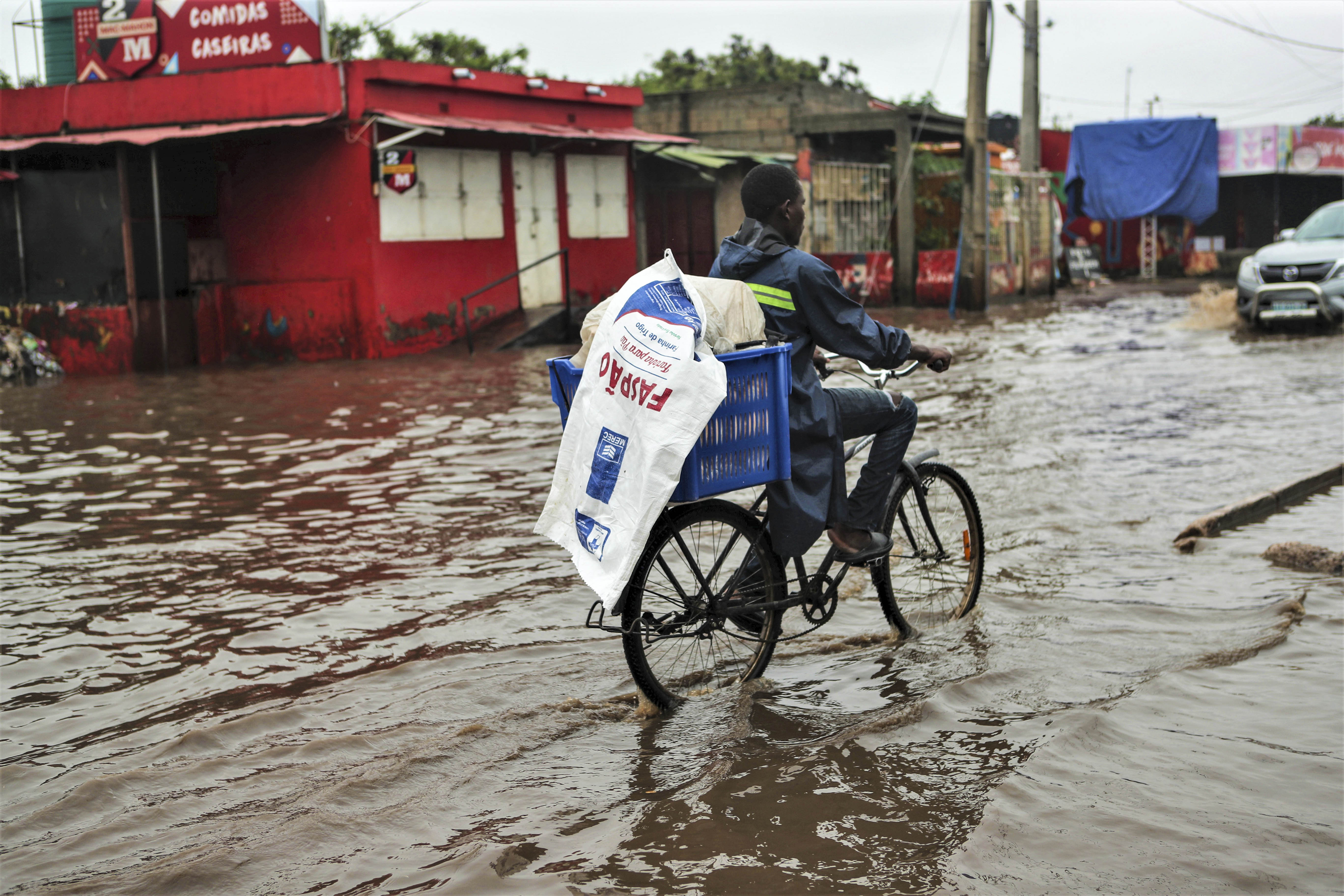 epa12653935 People walk through floodwaters in Maputo, Mozambique, 16 January 2026, after several days of continuous heavy rain. EPA/LUISA NHANTUMBO