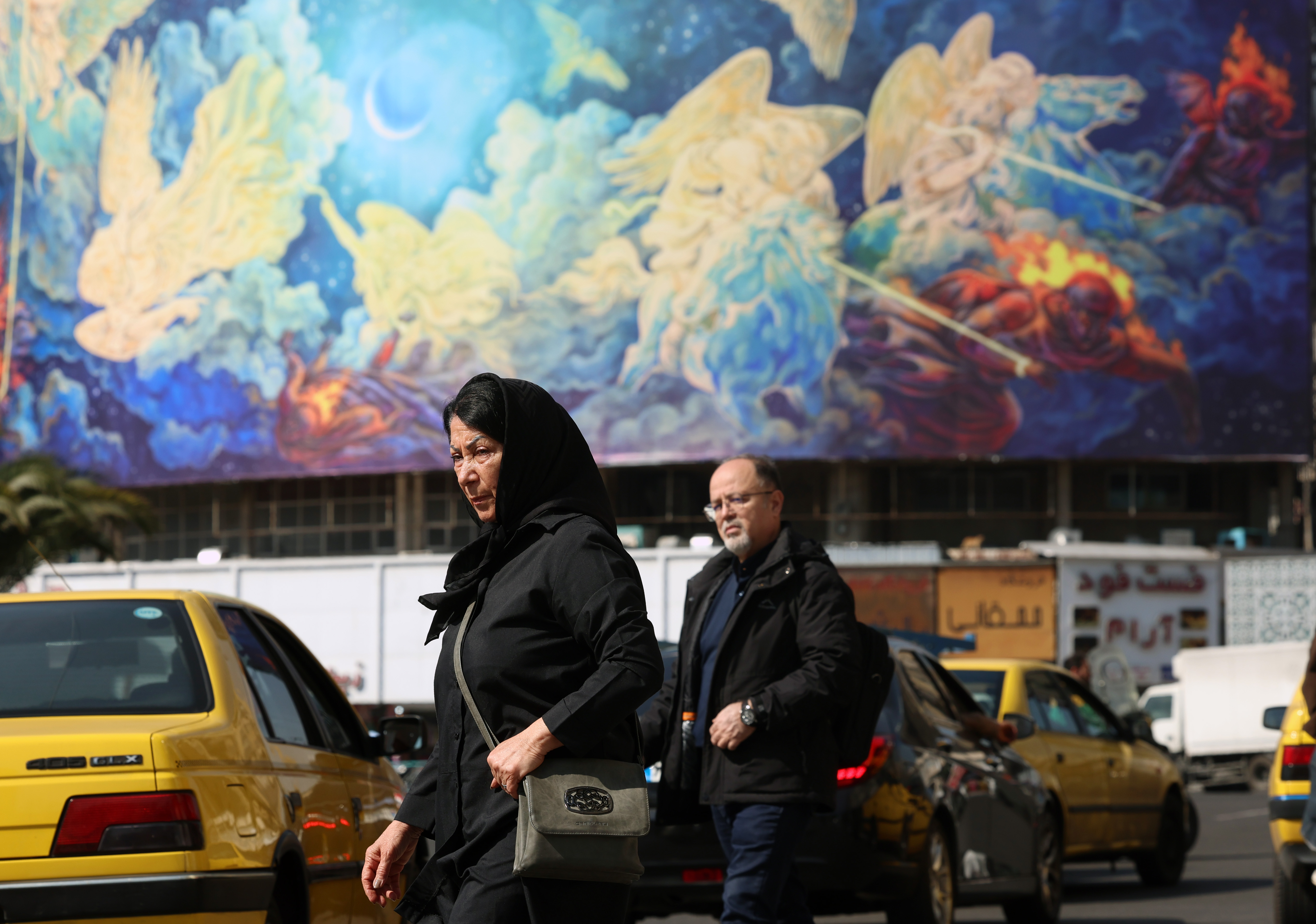 epa12764382 Iranians walk past a huge billboard carrying a poem interpretation in Persian 'Human will defeat the evils' at Valiasr Square in Tehran, Iran, 21 February 2026. As tension between Iran and US continue, US President Donald Trump said that he would wait for 10 to 15 days to reach a deal with the Iranian government. EPA/ABEDIN TAHERKENAREH