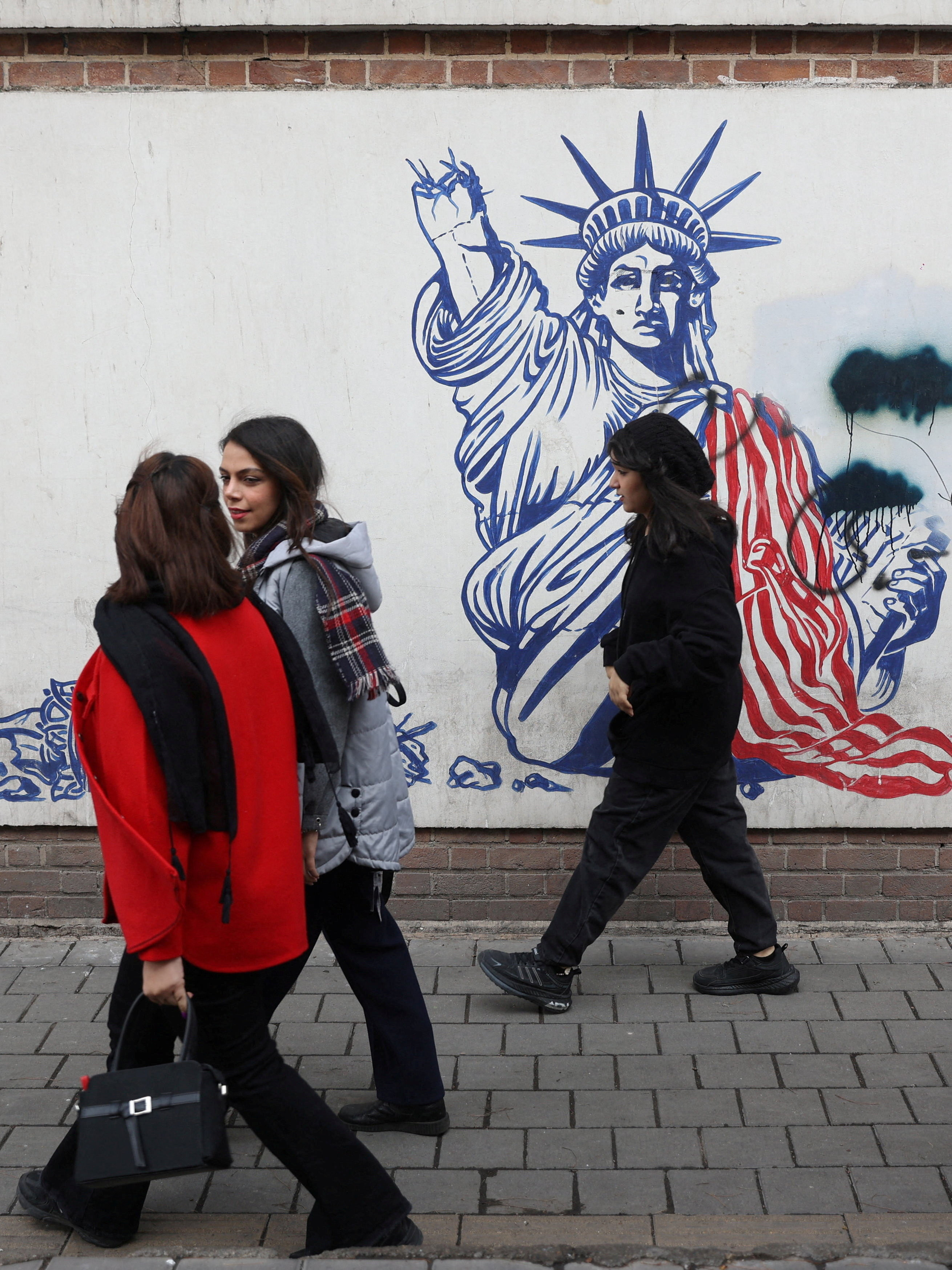 Women walk past an anti-U.S. mural on a street in Tehran, Iran, February 5, 2026. Majid Asgaripour/WANA (West Asia News Agency) via REUTERS ATTENTION EDITORS - THIS PICTURE WAS PROVIDED BY A THIRD PARTY