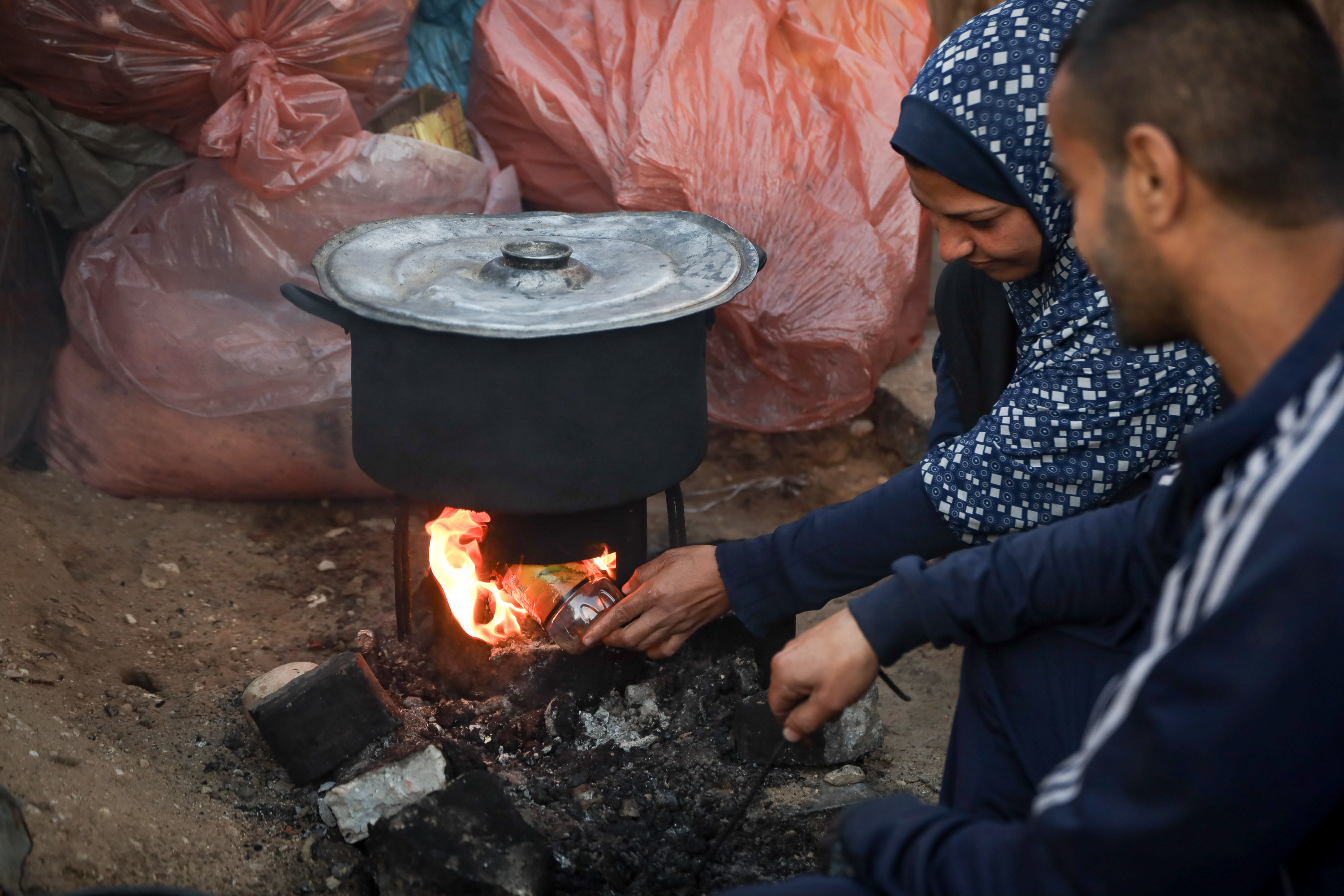 Iman Junaid and her husband Jihad rely on empty plastic bottles to fuel their cooking fire because they cannot afford the rising price of firewood