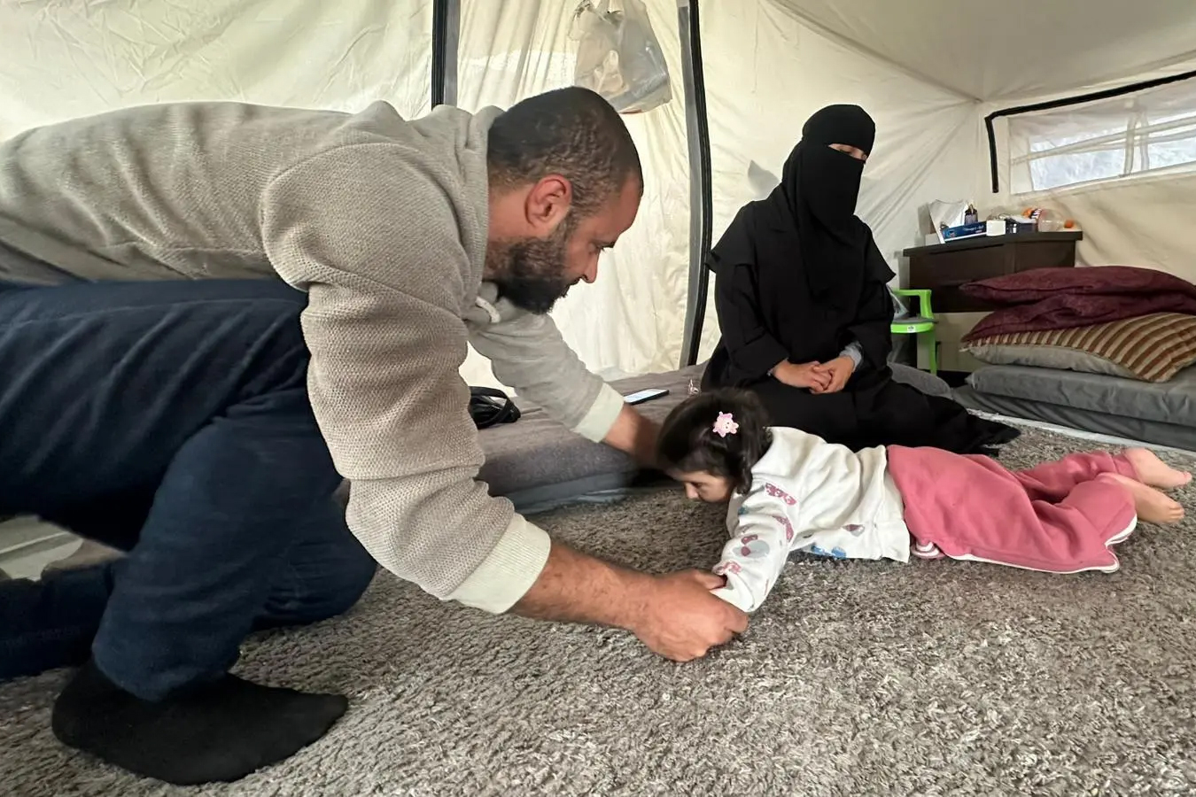 Nour Abu Samaan, who was paralyzed after inhaling toxic gas from Israeli strikes as a newborn, sits in a displacement tent. Doctors say she suffers from severe physical stiffness that is described as more severe than partial paralysis.