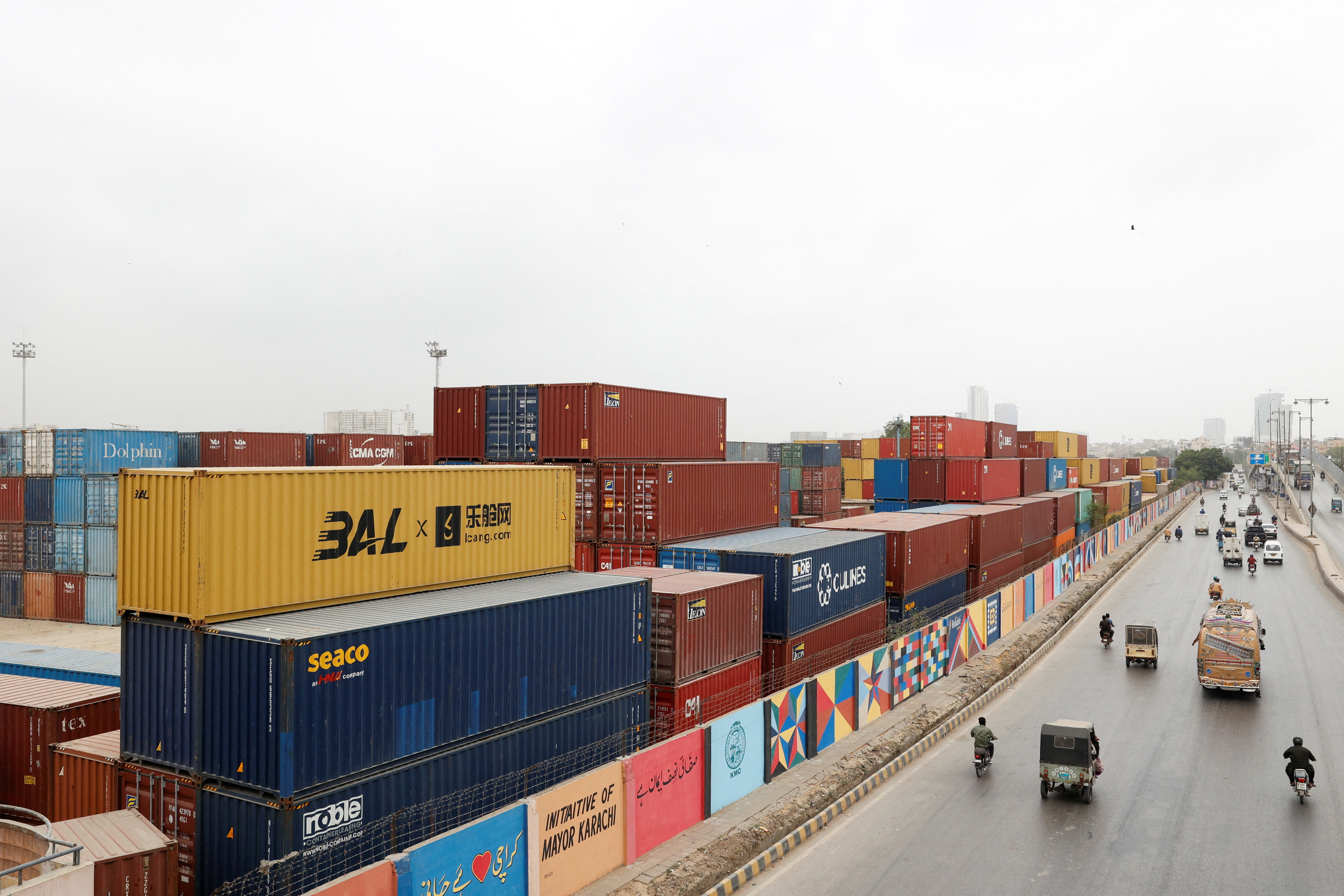 Vehicles move past a warehouse yard with shipping containers near port area in Karachi, Pakistan, July 31, 2025. REUTERS/Akhtar Soomro