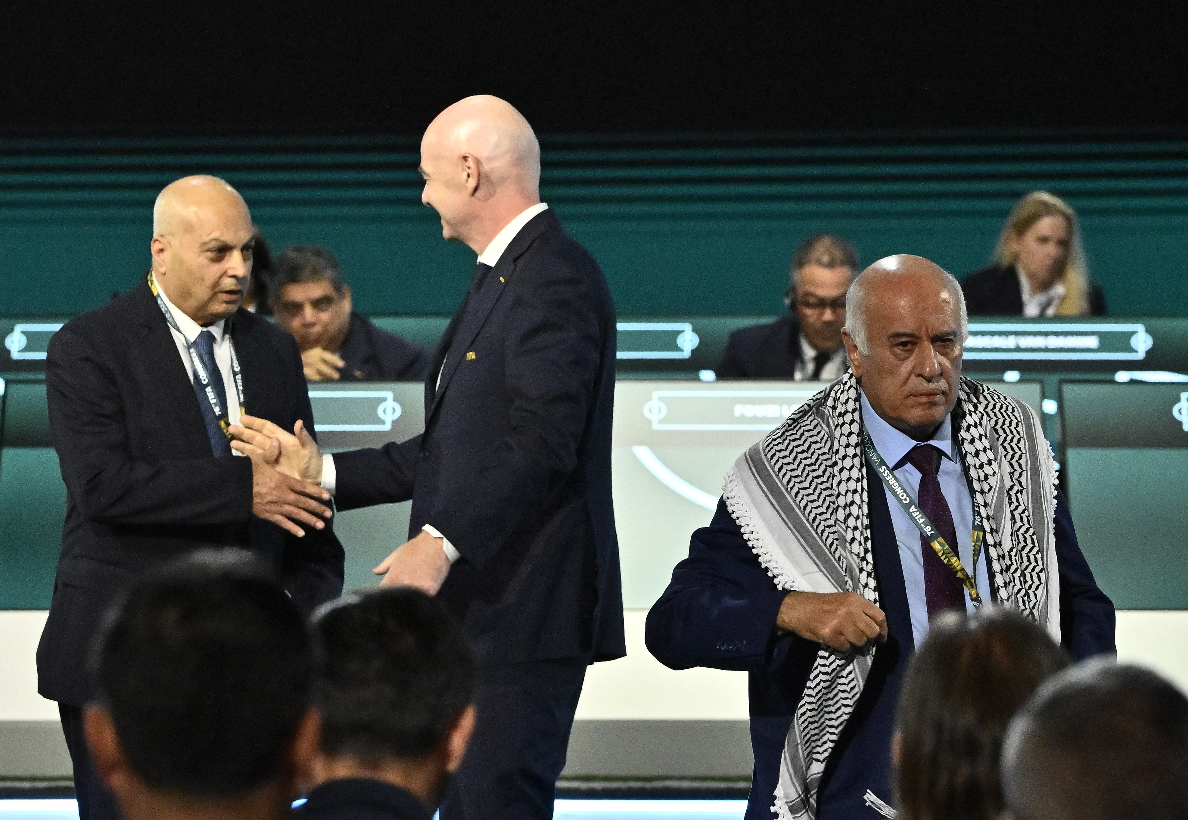 FIFA President Gianni Infantino shakes hands with Moshe Zuares, President of the Israeli football federation as Jibril Rajoub, President of the Palestine Football association leaves the stage during the congress