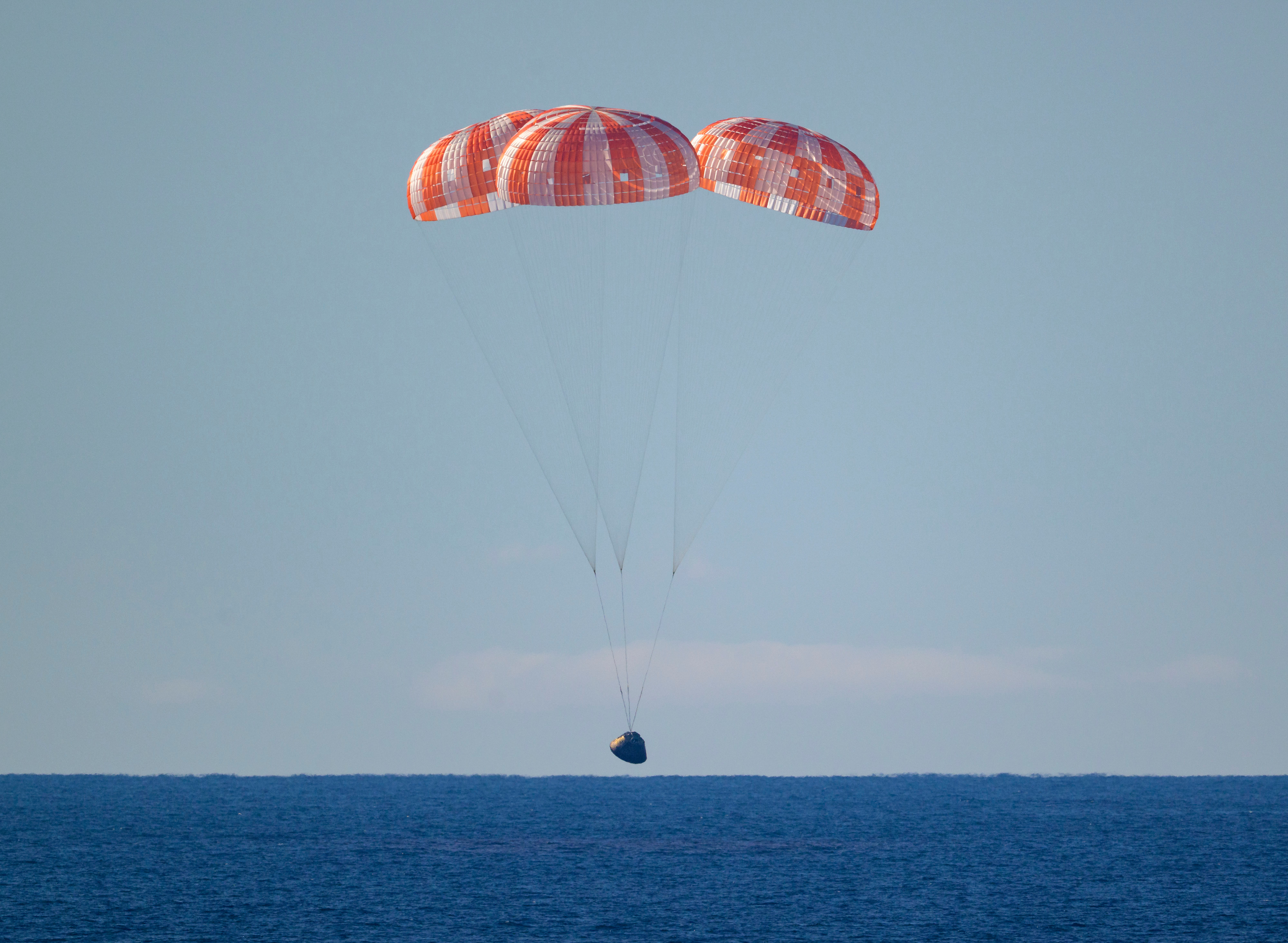The Orion spacecraft with Artemis II crewmembers aboard approaches the surface