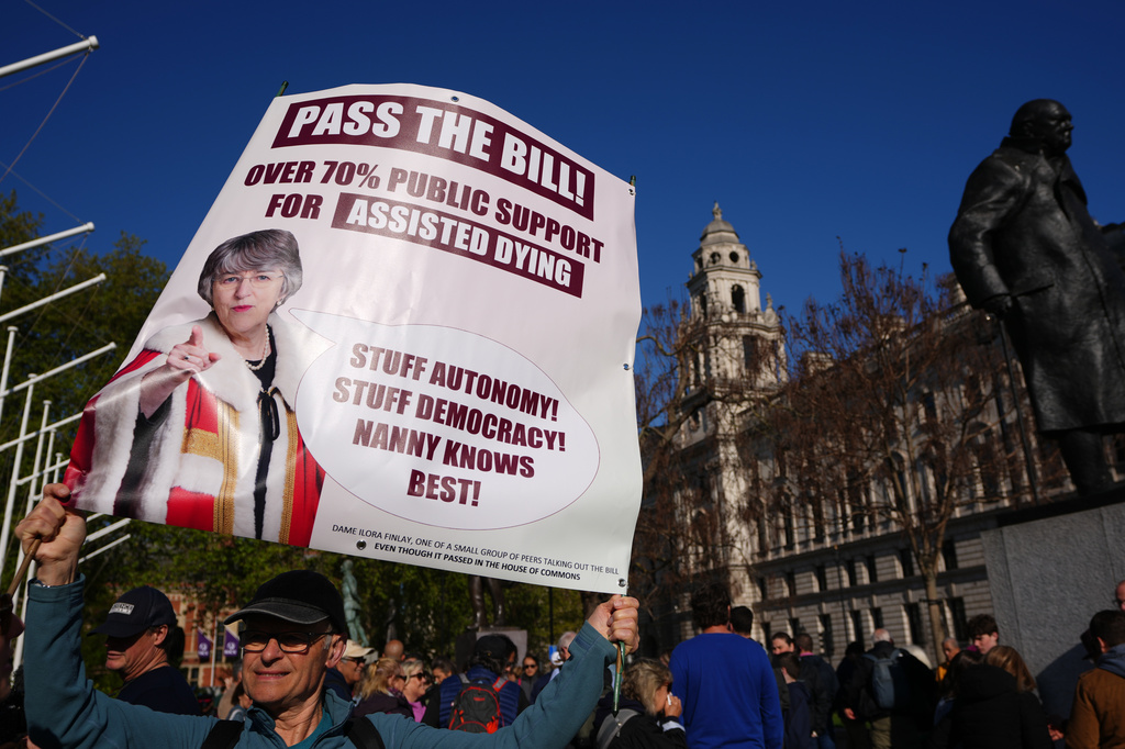 An assisted dying campaigner holds a banner outside parliament in London