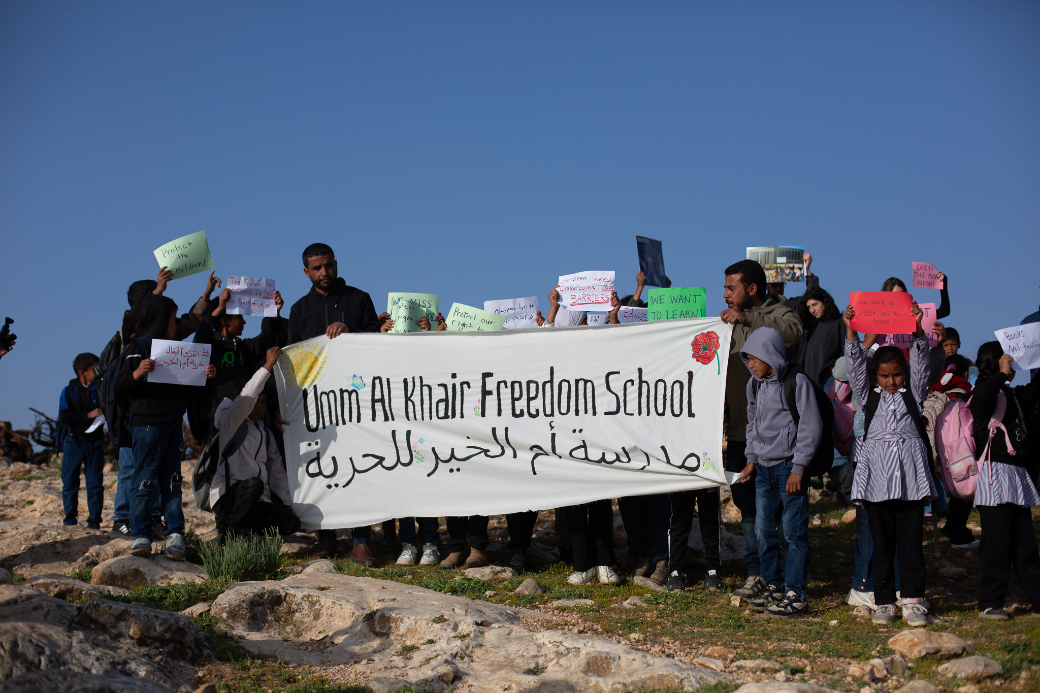 Khalil and Tareq hold banner with kids [Jacob Lazarus/Al Jazeera]
